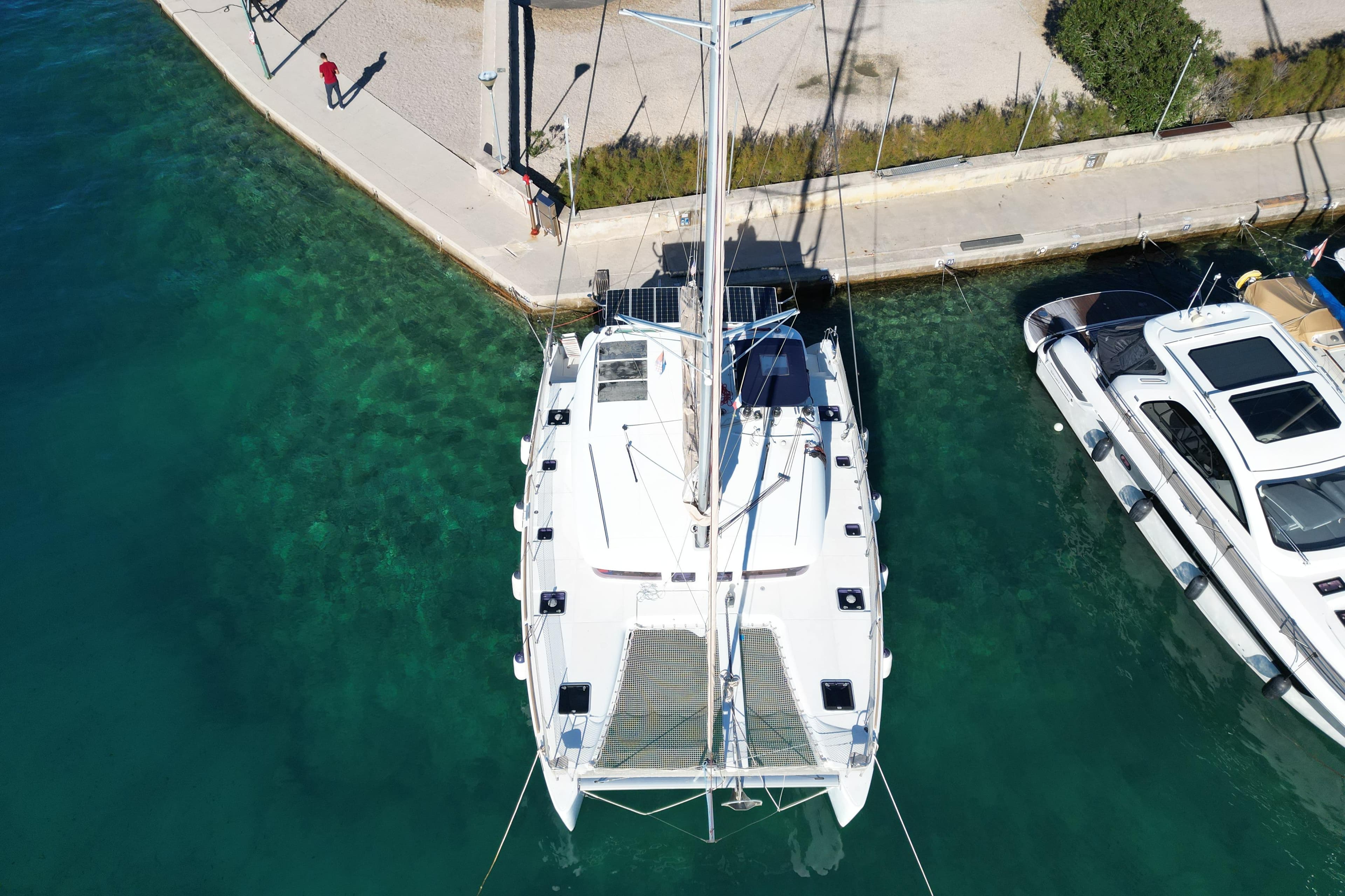 Aerial view of a 2014 Lagoon 400 S2 catamaran docked in clear turquoise water.