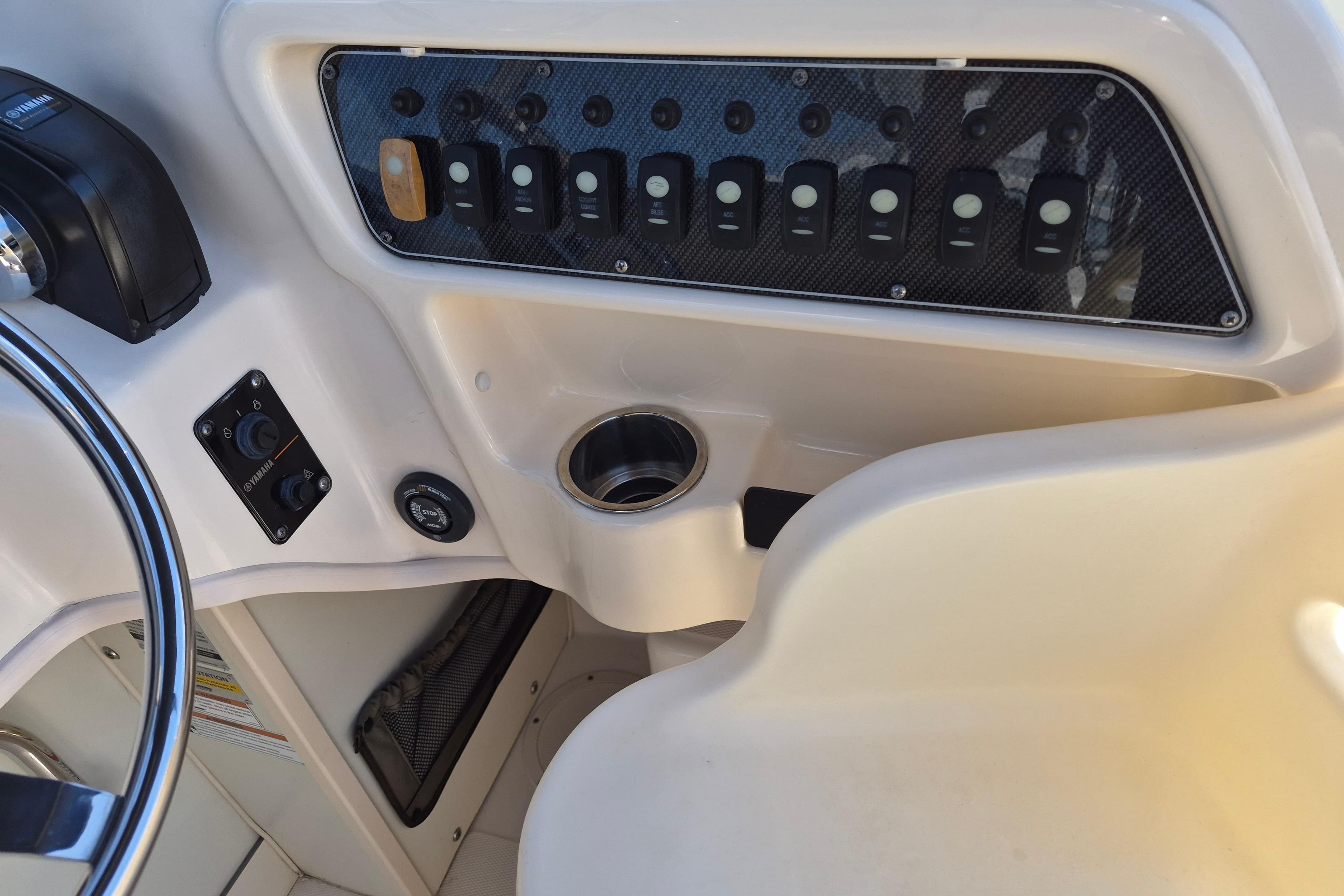 Control panel of a 2022 Grady-White Adventure 208 boat with switches and steering wheel.