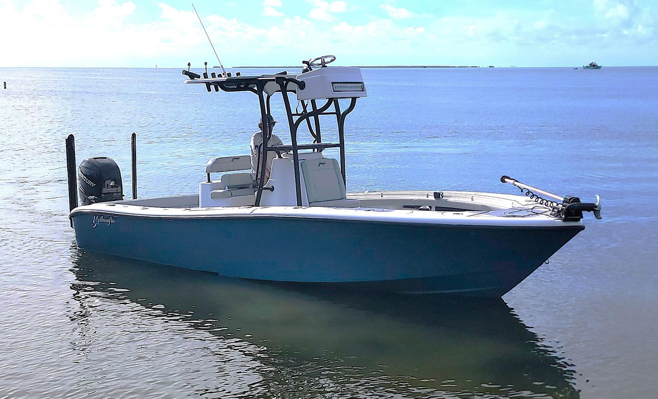 2021 Yellowfin 26 Hybrid boat on calm water under a clear sky.