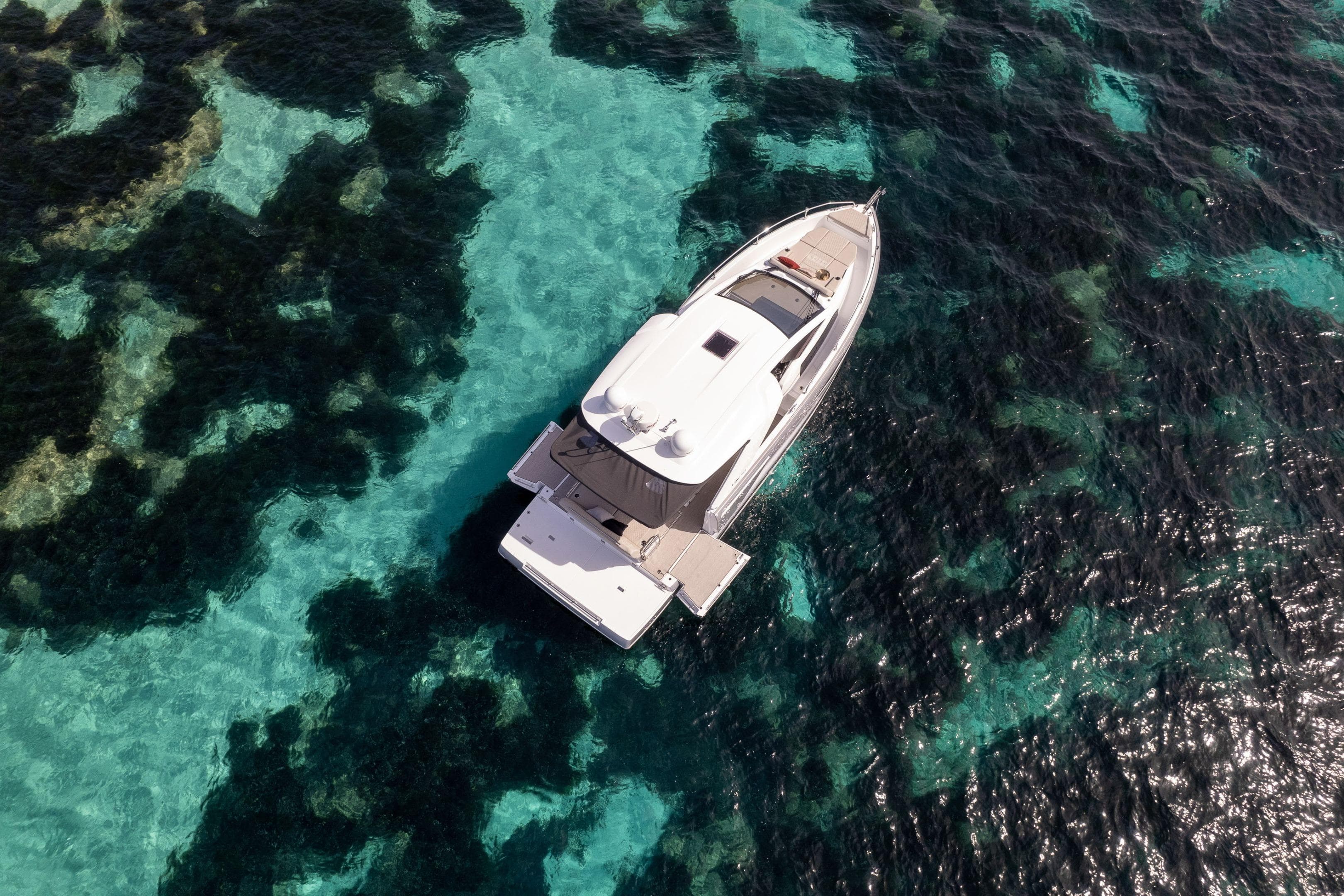 Aerial view of 2026 Jeanneau DB/37 IB yacht on clear turquoise water.
