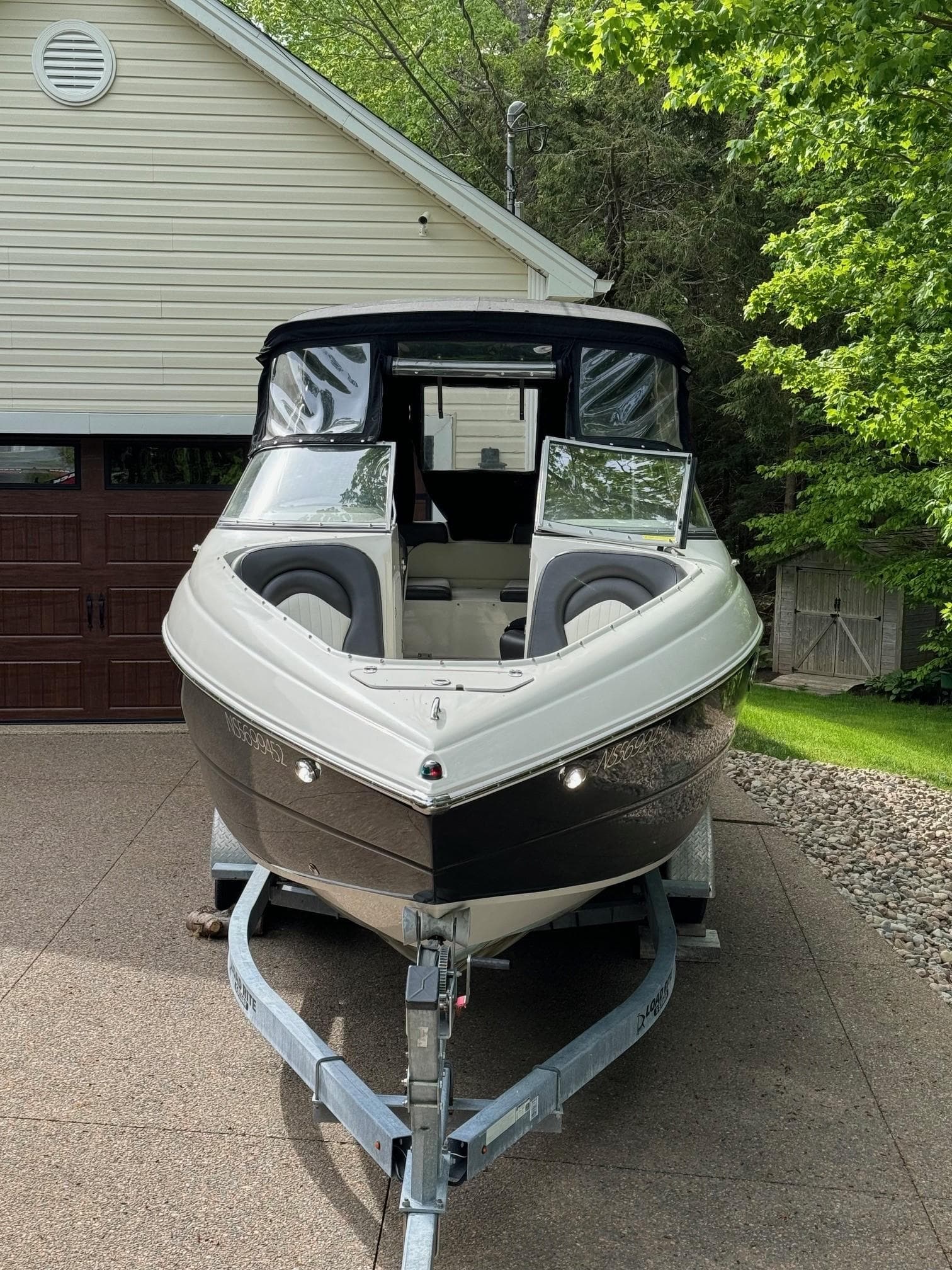 2017 Stingray 250 LR boat on trailer, parked in driveway near garage and trees.