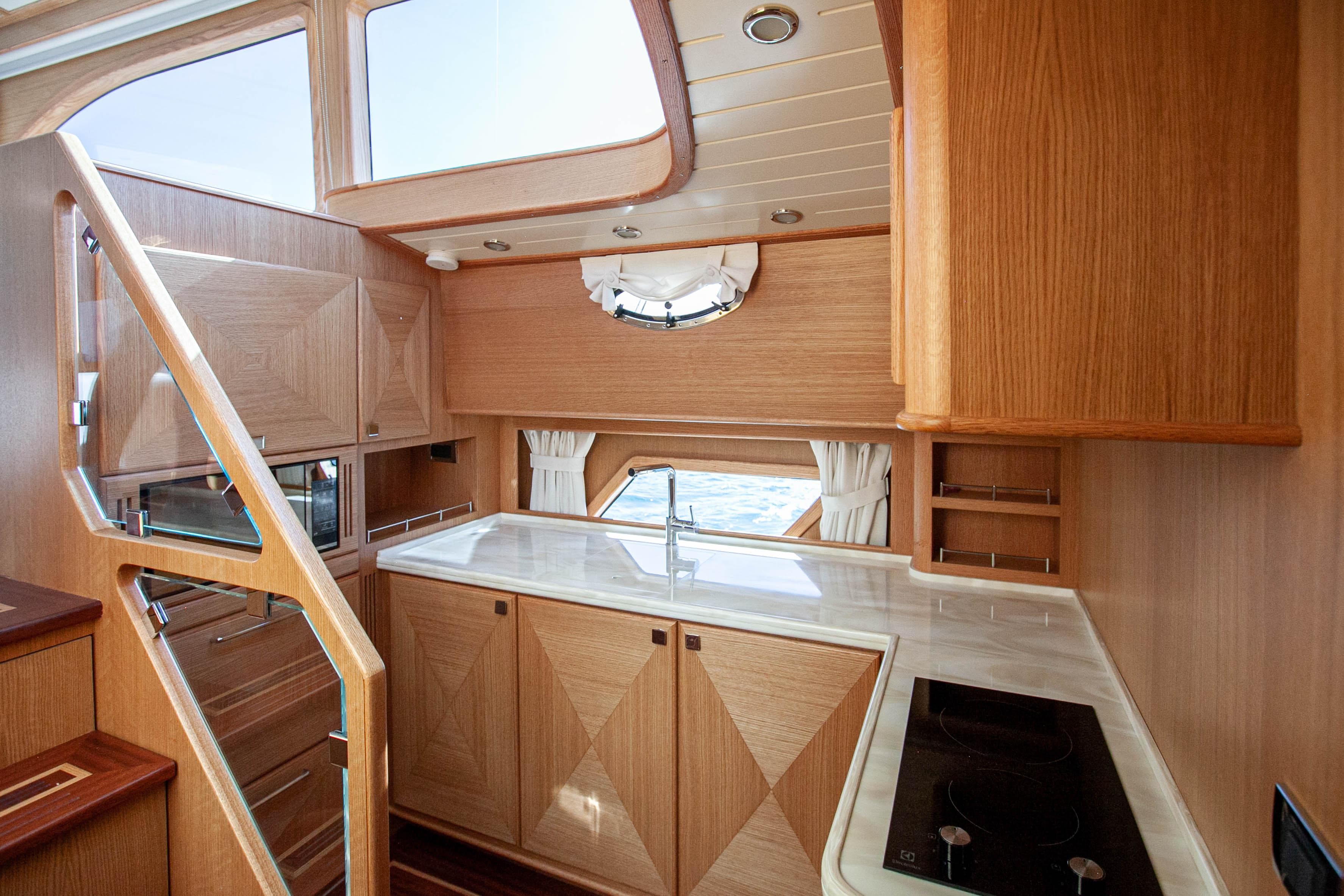 Luxurious 2023 Vicem 55 yacht interior with modern kitchen design and wooden cabinetry.