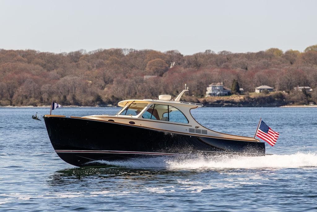 2014 Hinckley Talaria 34 cruising on a scenic lake with American flag.
