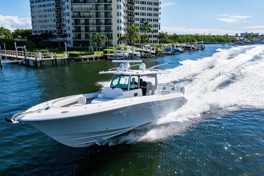 2024 HCB 42 Lujo boat cruising on water near waterfront buildings.