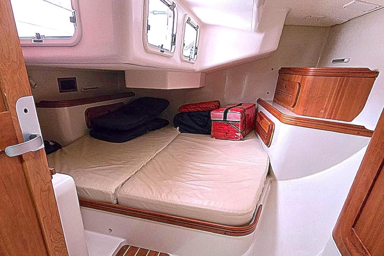 Cozy cabin interior of a 2004 C&C 121 sailboat with cushioned seating and wooden accents.