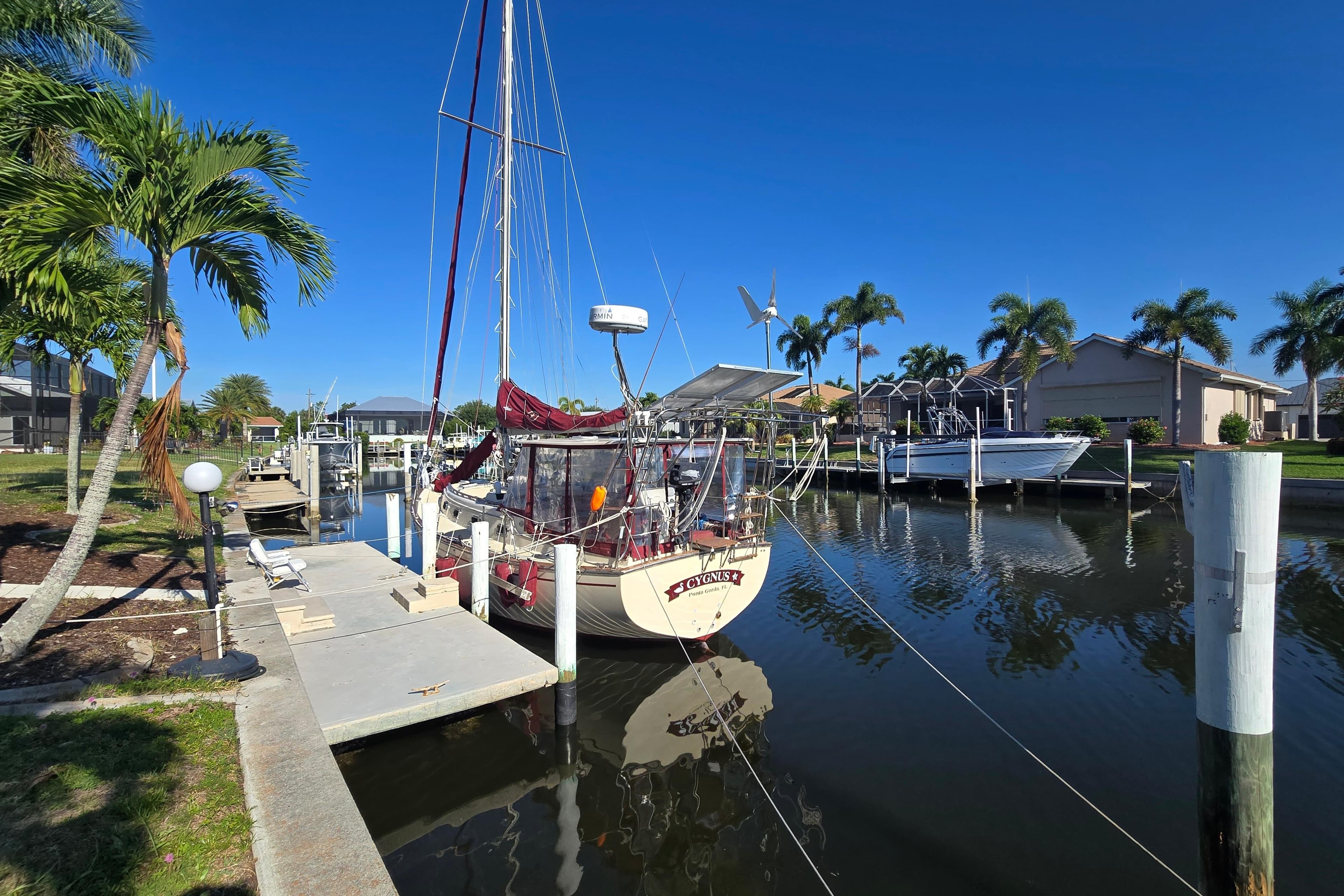 1989 Island Packet 35 sailboat docked in a sunny marina with palm trees.