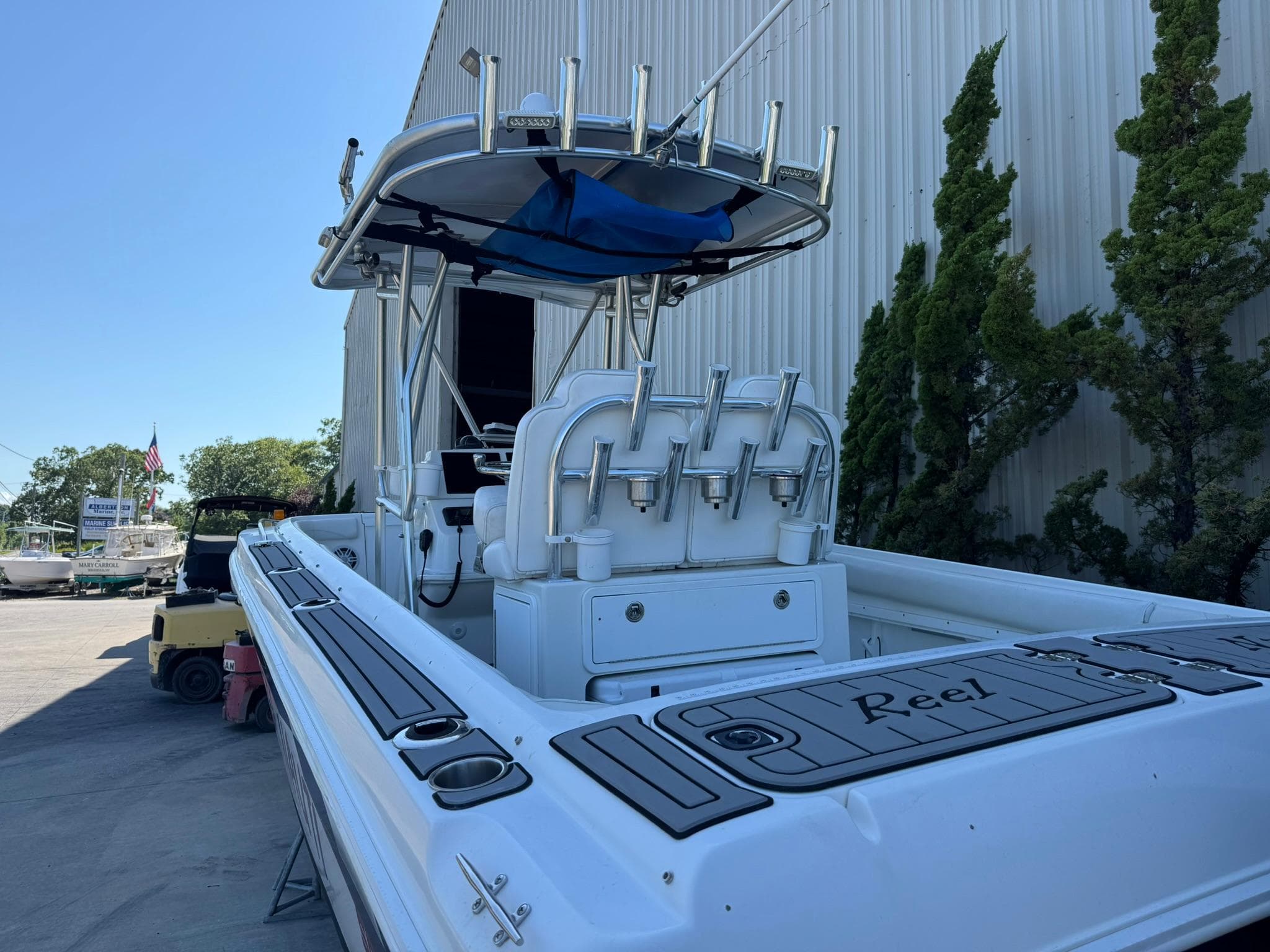 1998 Wellcraft Scarab Sport 302 boat with fishing rod holders, docked near a warehouse.