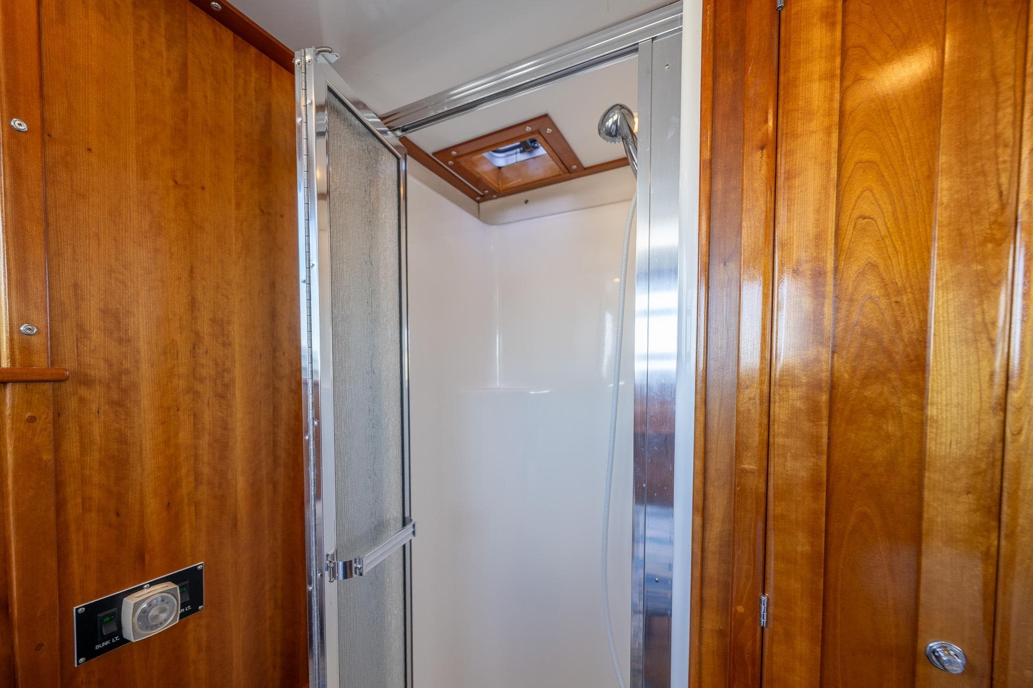 Shower area in 1999 Rozema Boat Works Custom 40, featuring wooden paneling and glass door.