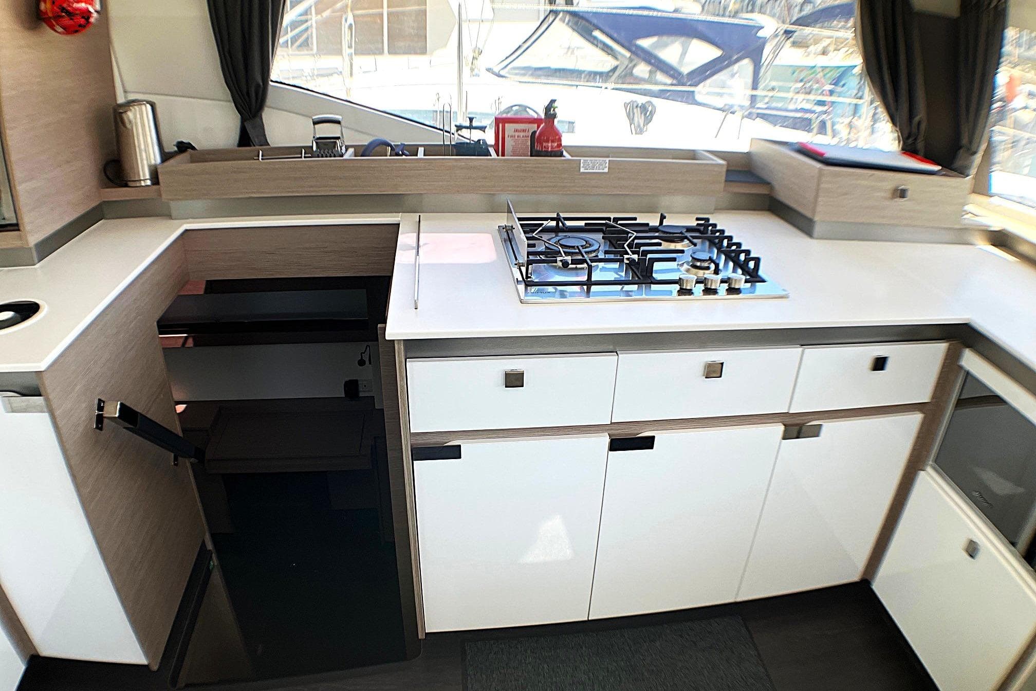 Modern kitchen interior of 2023 Fountaine Pajot Elba 45 Catamaran with stove and cabinetry.