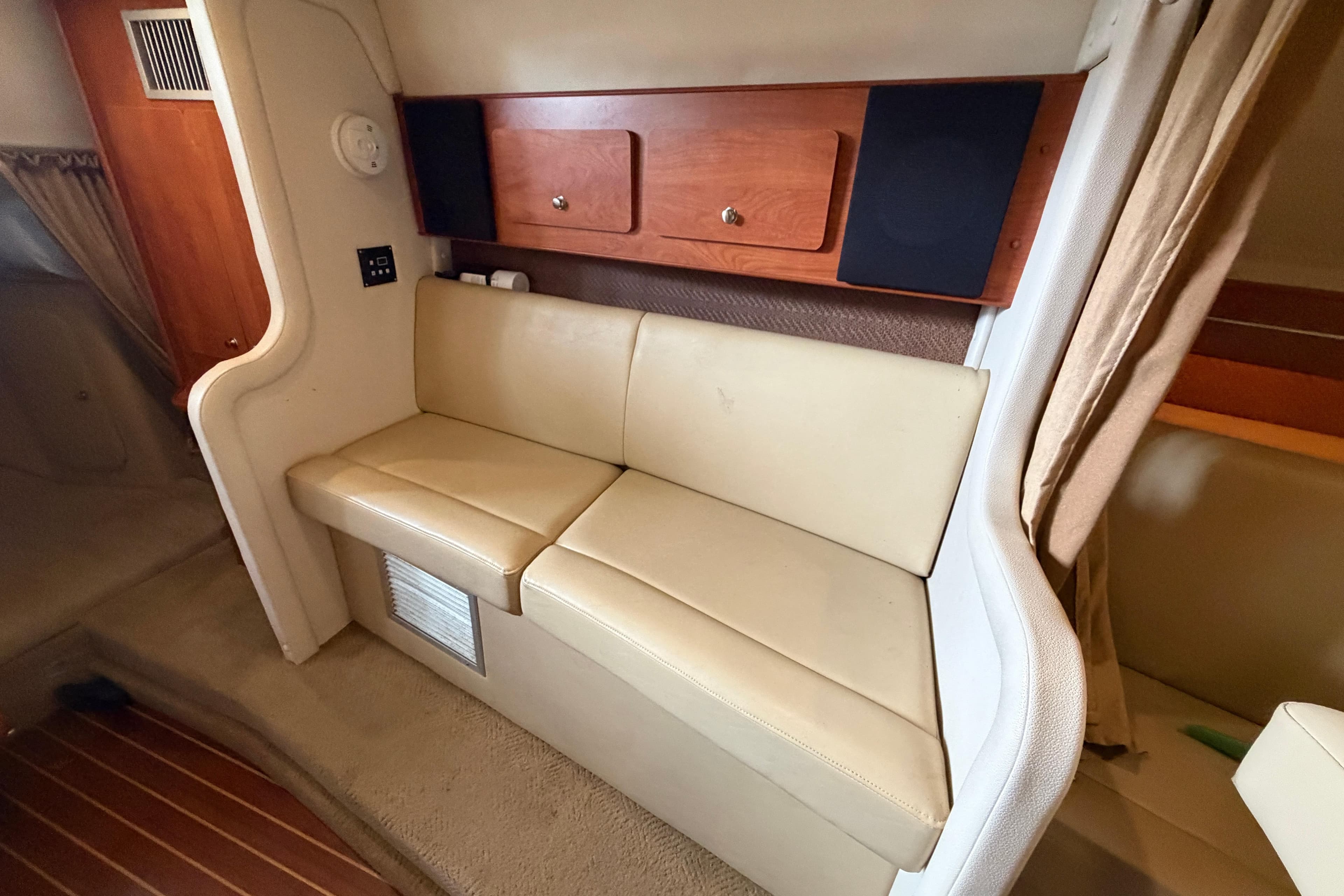 Interior of a 2006 Rinker 300 Express Cruiser with beige seating and wooden cabinetry.