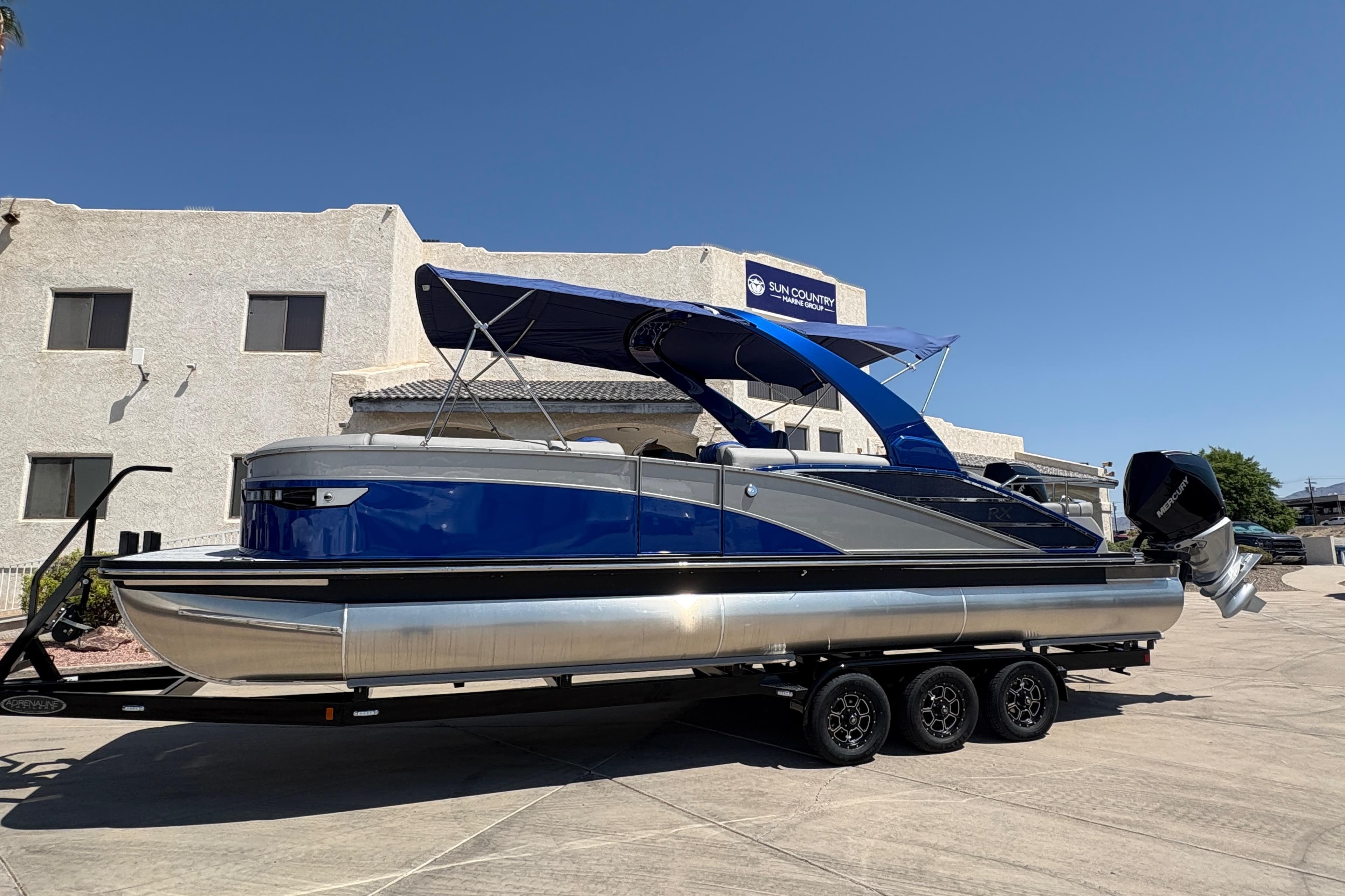 2026 Bennington 27 RXSBAT2 pontoon boat with blue canopy on a trailer.