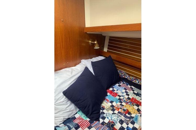Cozy cabin interior of 1986 Nonsuch 30 Ultra with colorful quilt and pillows.