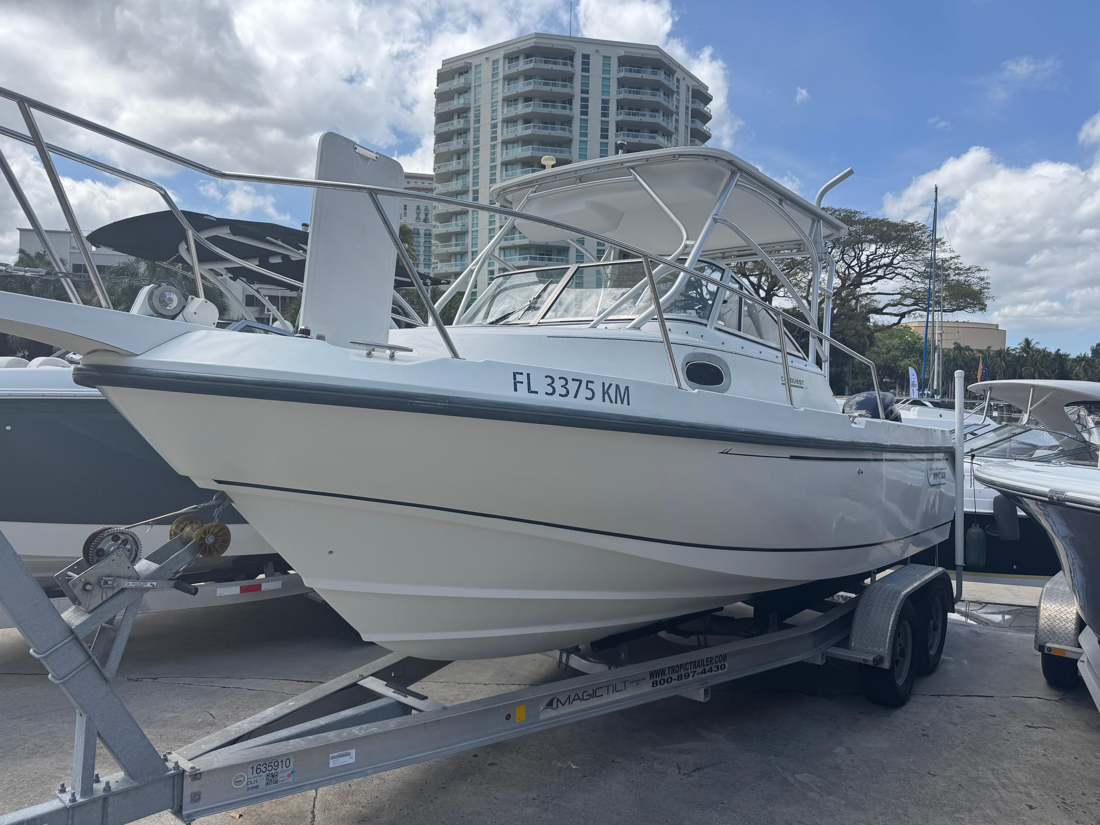1999 Boston Whaler Conquest 23 boat on trailer, parked near high-rise buildings.