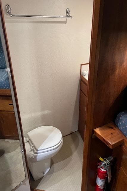1972 DeFever 38 Passagemaker bathroom with toilet, wooden cabinetry, and fire extinguisher.