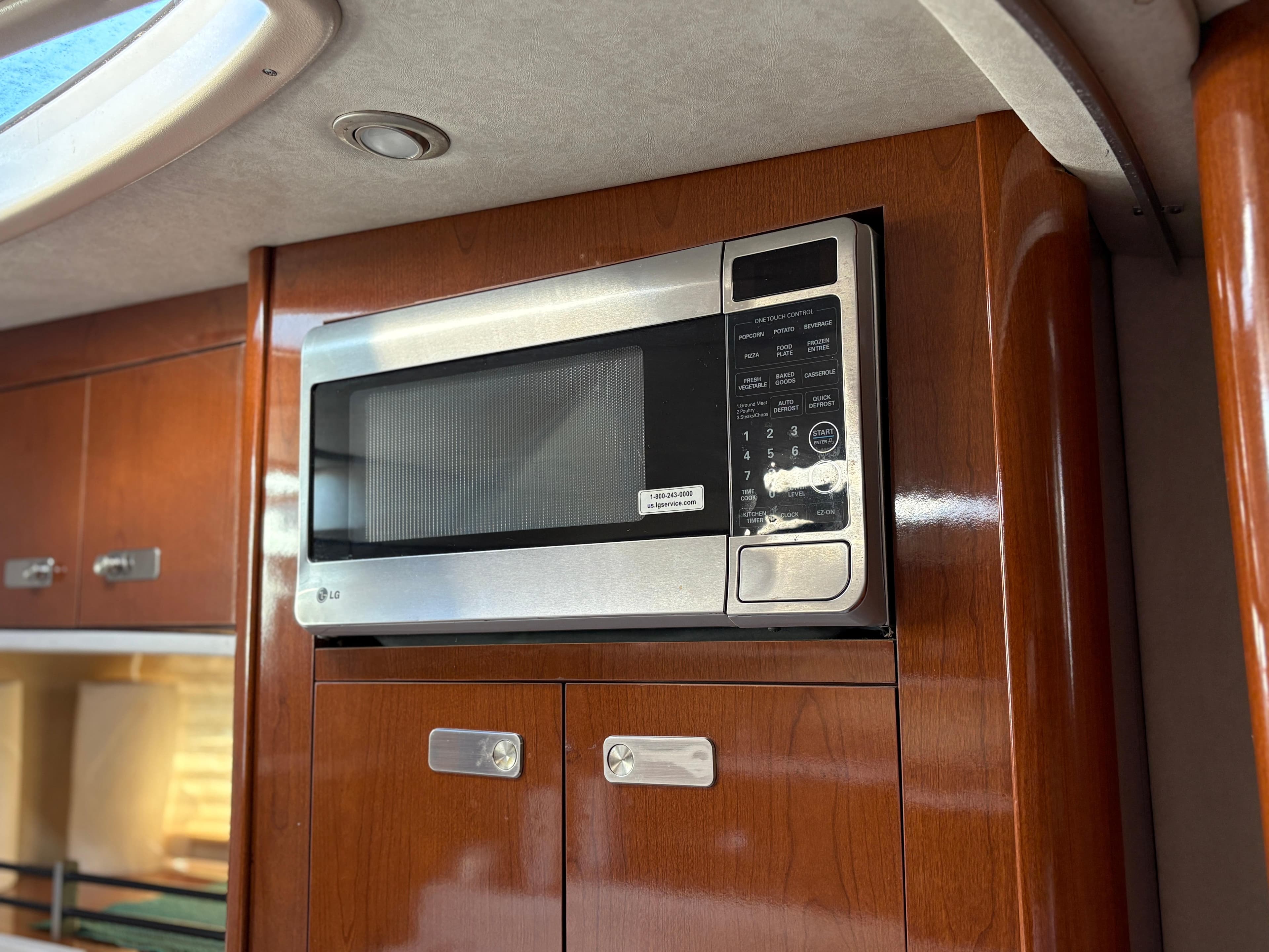 Microwave in 2012 Sea Ray 350 Sundancer yacht kitchen with wooden cabinetry.