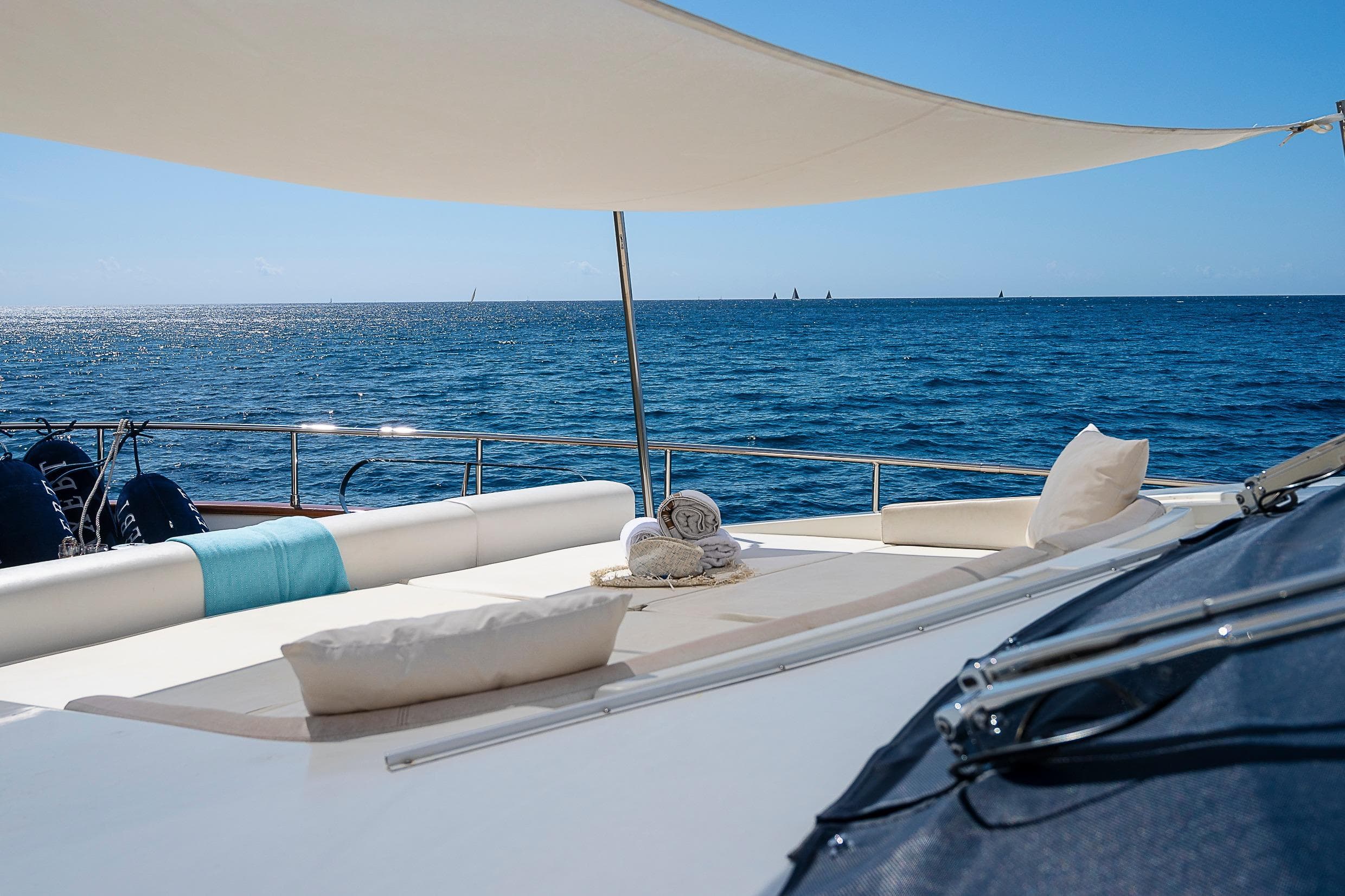 Luxurious Sanlorenzo 82 yacht deck with ocean view, featuring sunbathing area and shade sail.