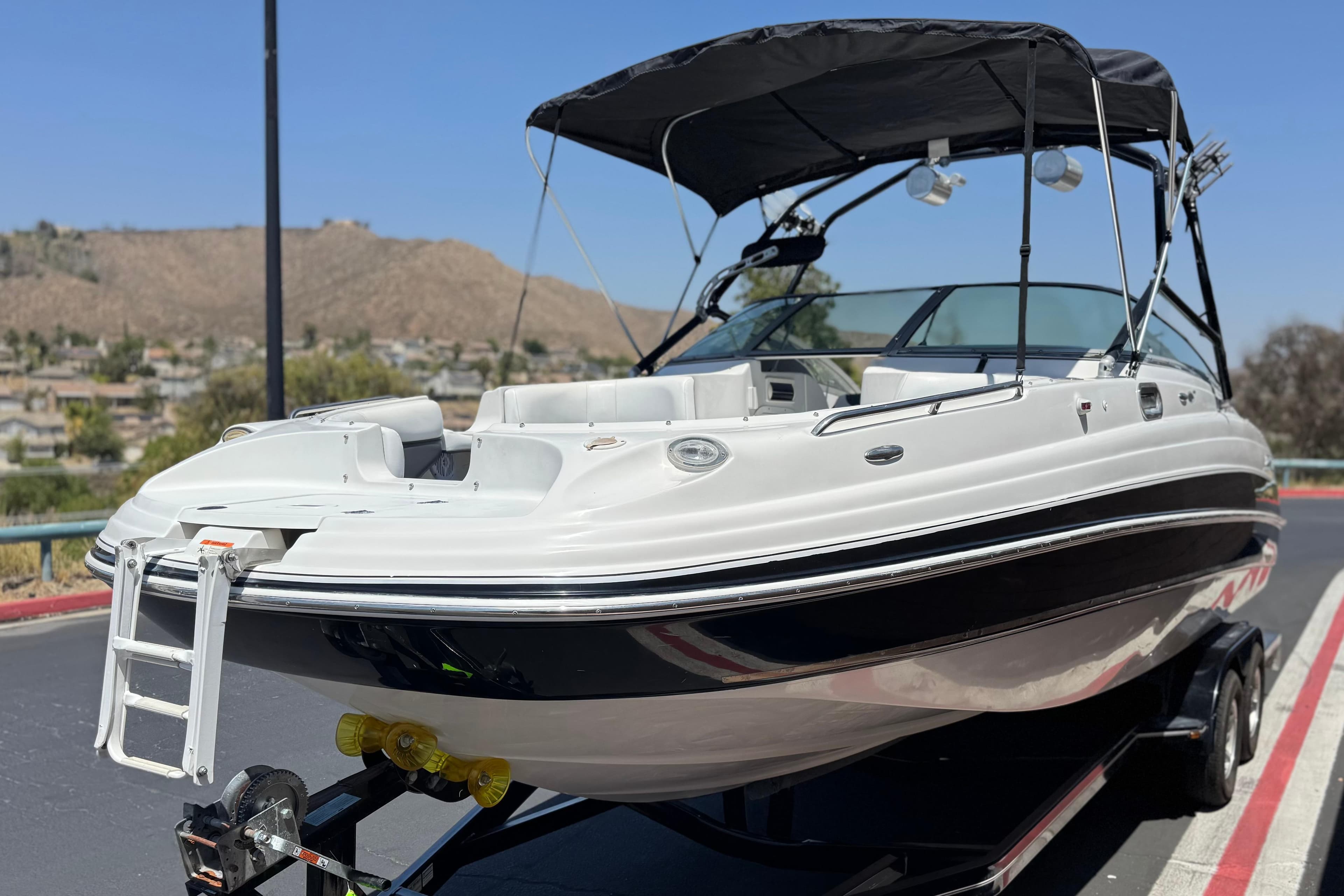 2003 Four Winns 264 Funship boat with canopy, parked on trailer, scenic background.
