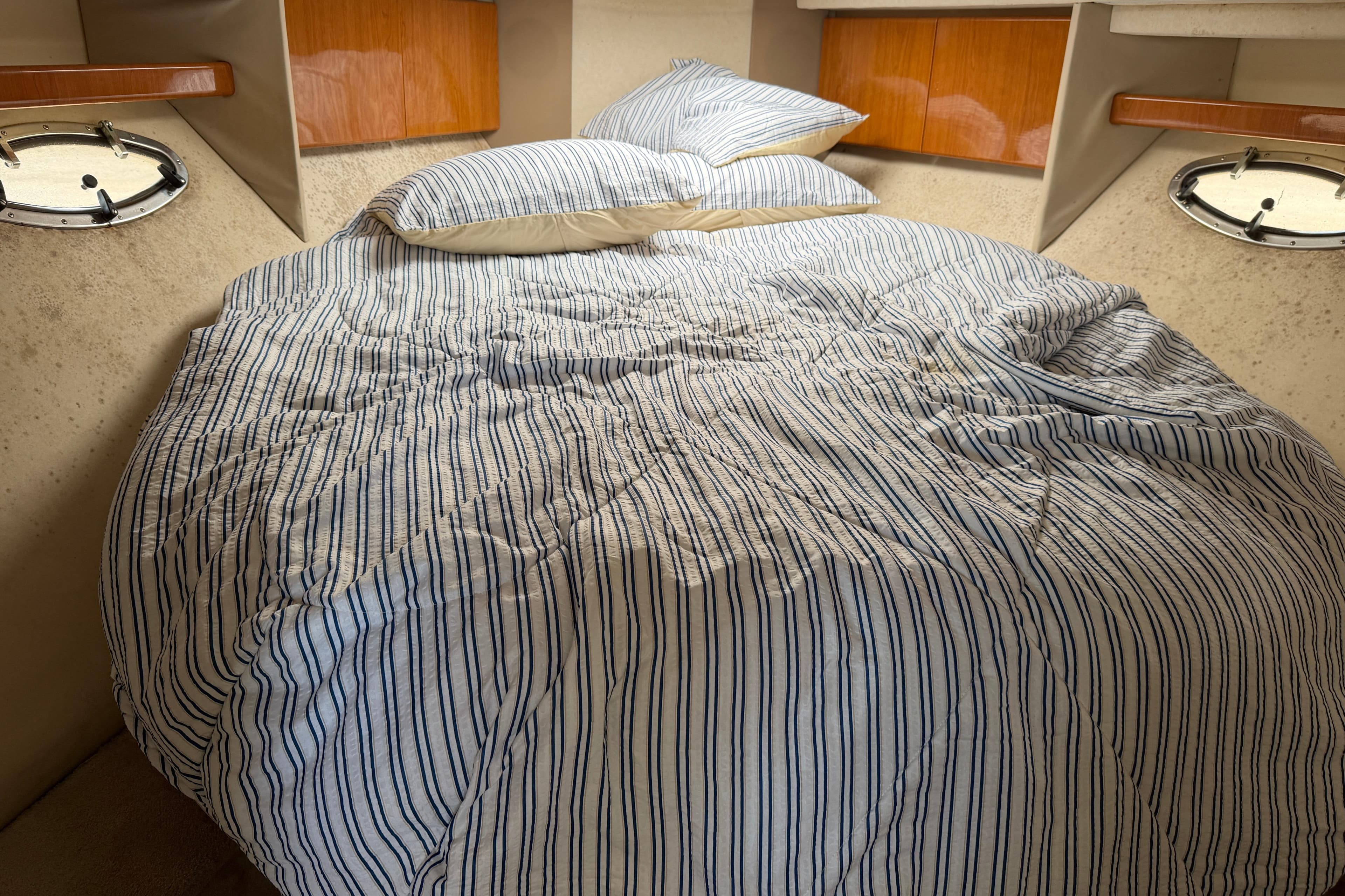 Cozy cabin interior of 2000 Formula 41 Performance Cruiser with striped bedding.