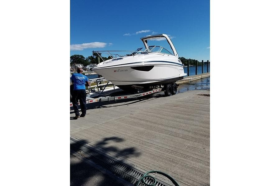 2018 Regal 28 Express boat on trailer at dockside under clear blue sky.
