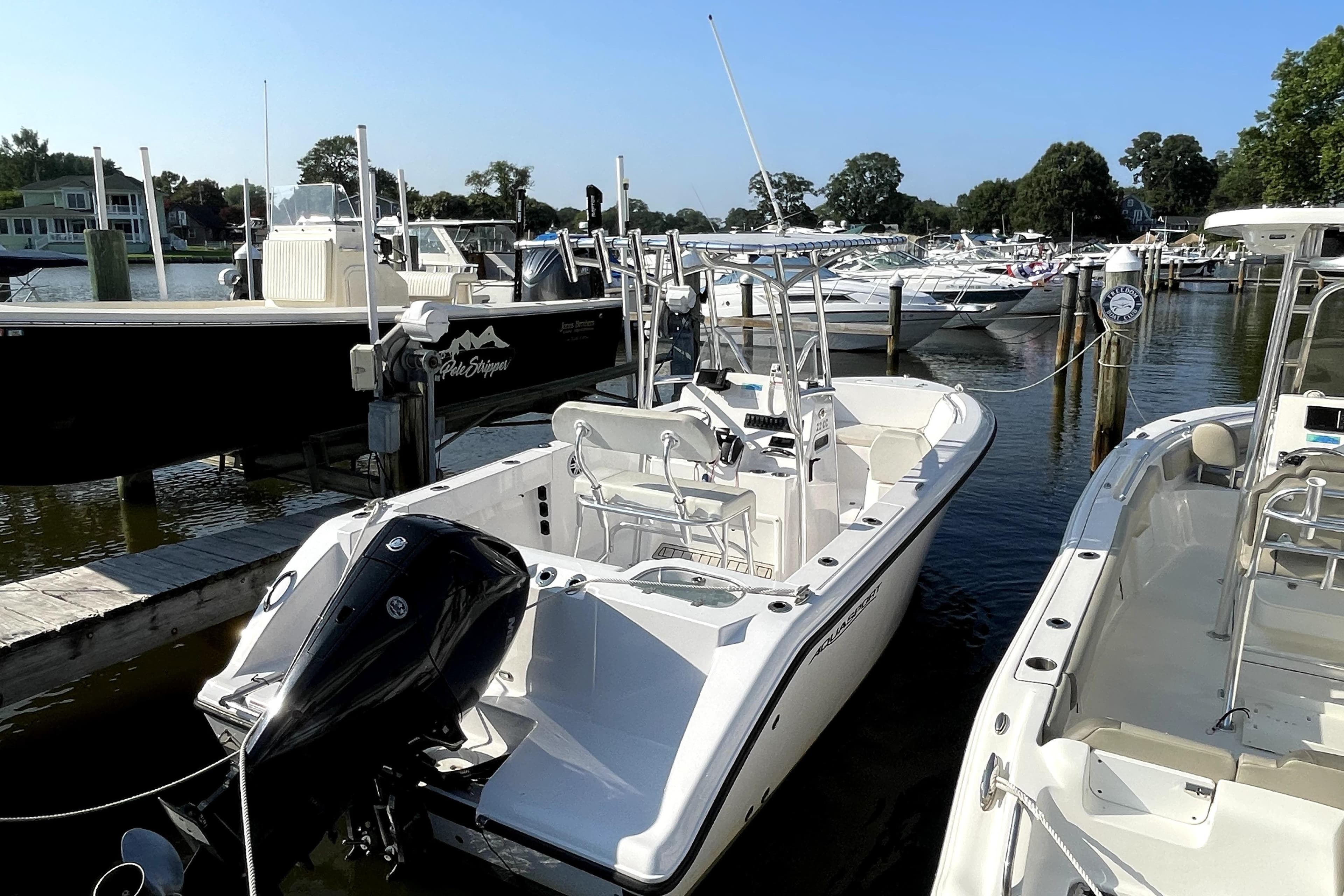 2024 Aquasport 2200 Center Console boat docked at a marina.