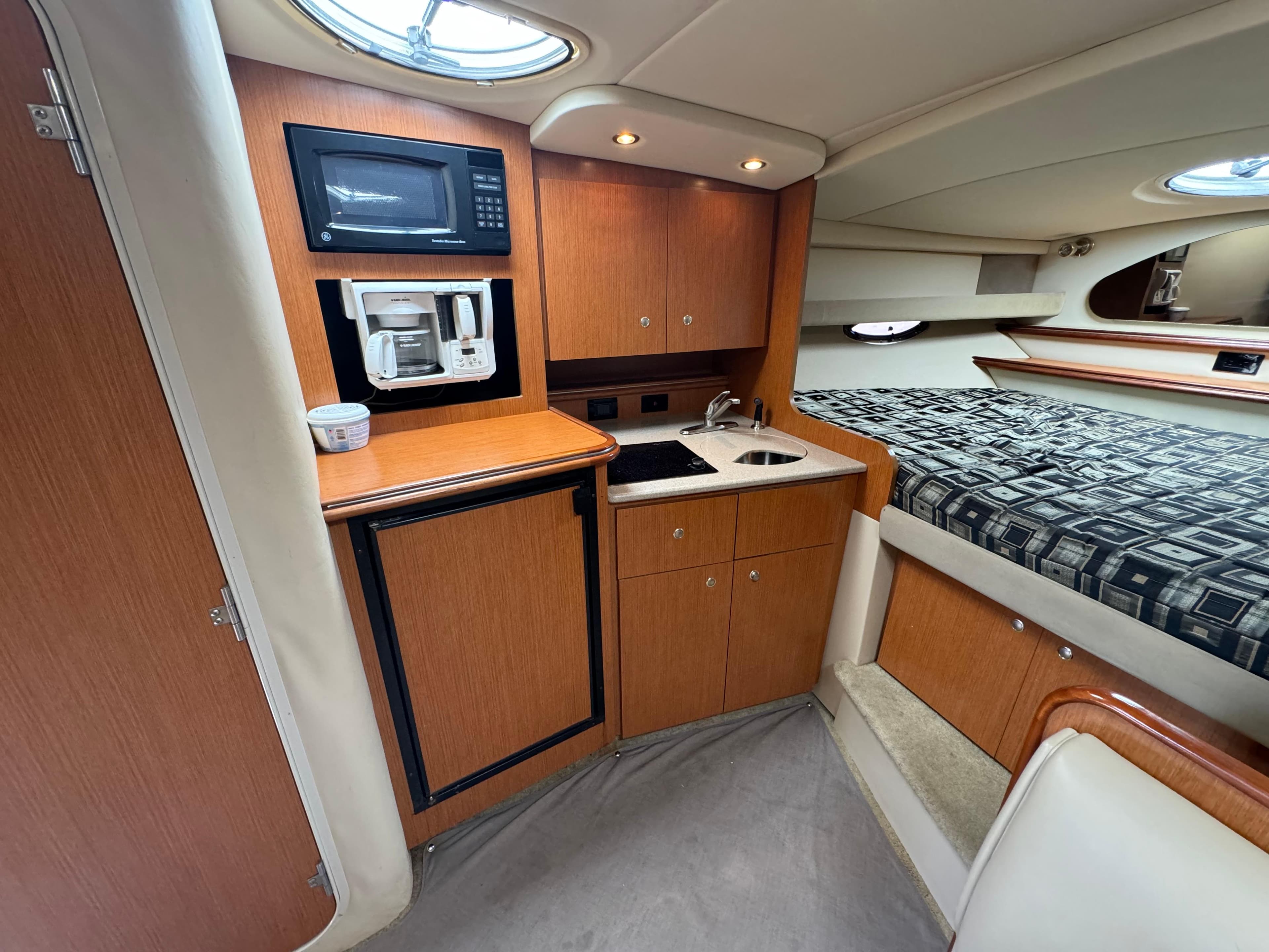 2004 Cruisers Yachts 320 Express interior with kitchenette and bed, featuring wood cabinetry.