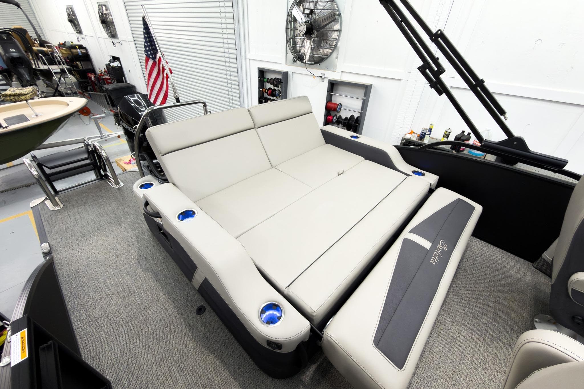 2025 Barletta Cabrio 24UC boat interior with convertible seating and cup holders in a garage setting.