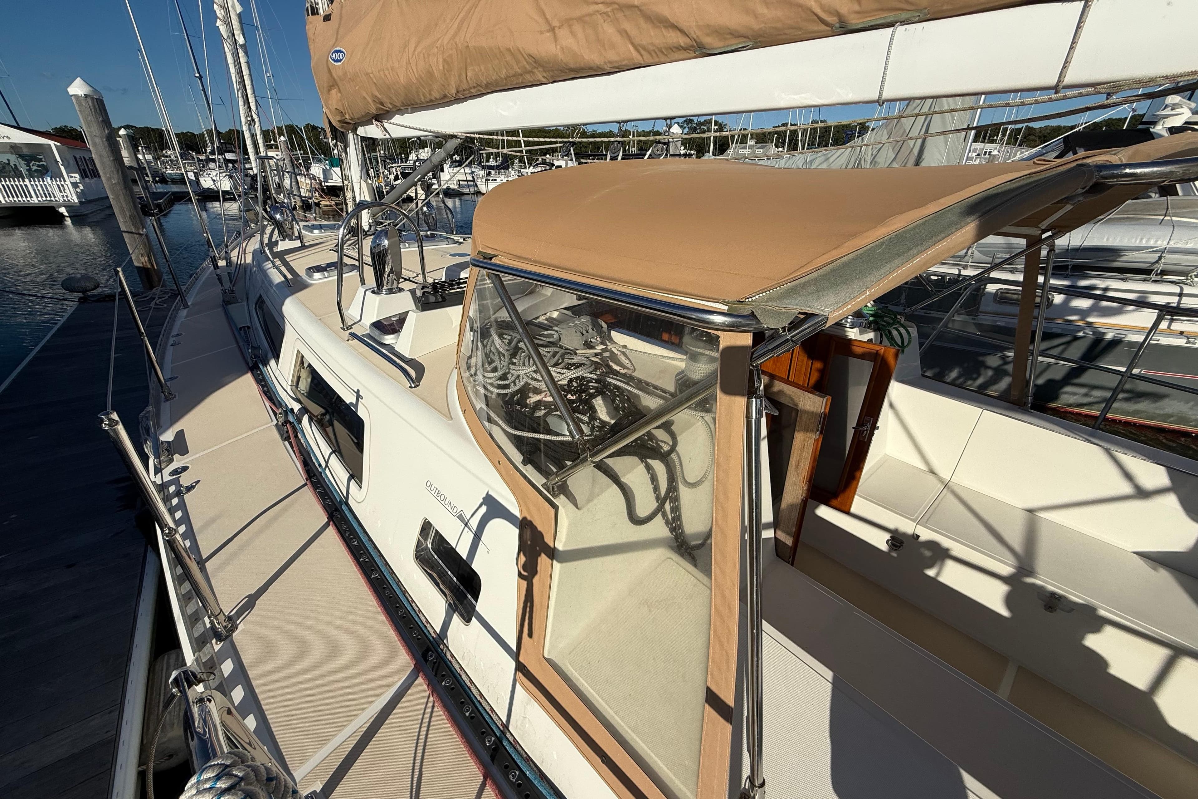 Sailboat docked at marina, Outbound 46 model, 2012, with tan canopy and clean deck.