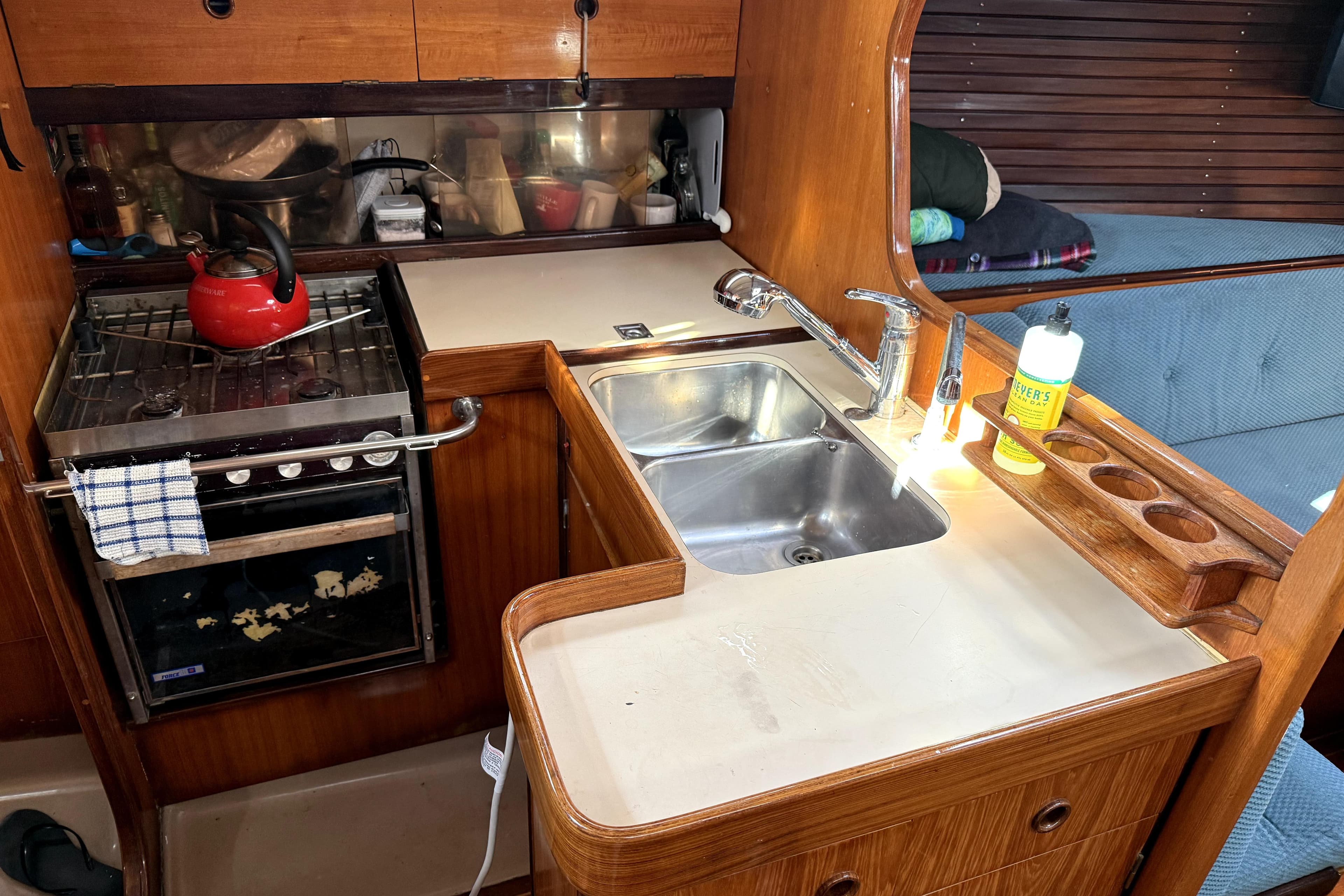 1985 Beneteau First 38 yacht kitchen with stove, sink, and wooden cabinetry.