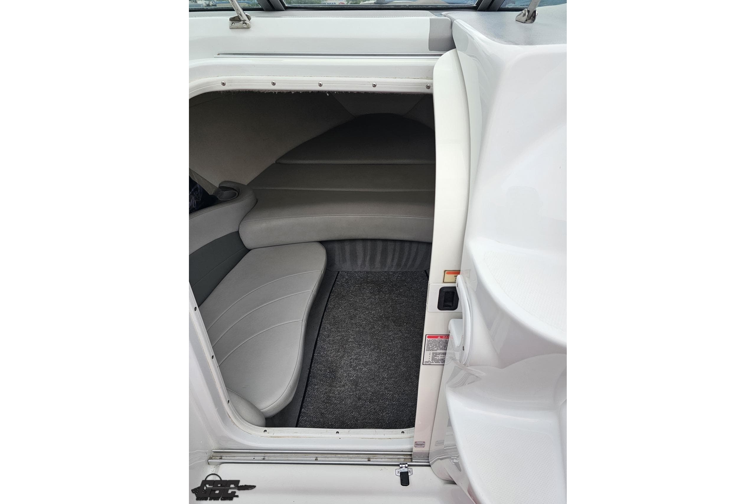 Interior cabin of a 2004 Baja 275 boat with gray seating and carpet.