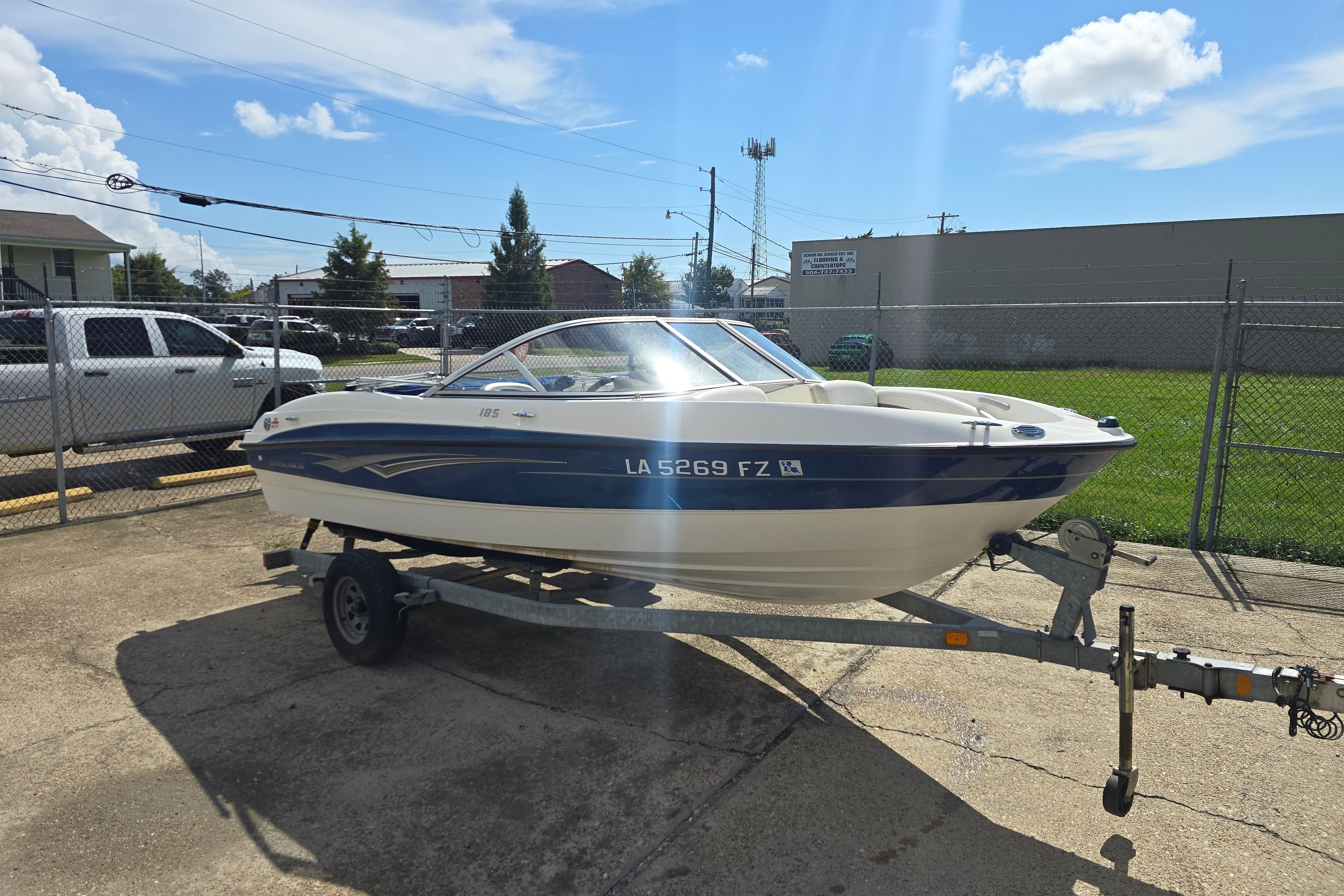 2010 Bayliner 185 Bowrider on trailer, parked outdoors under a clear blue sky.