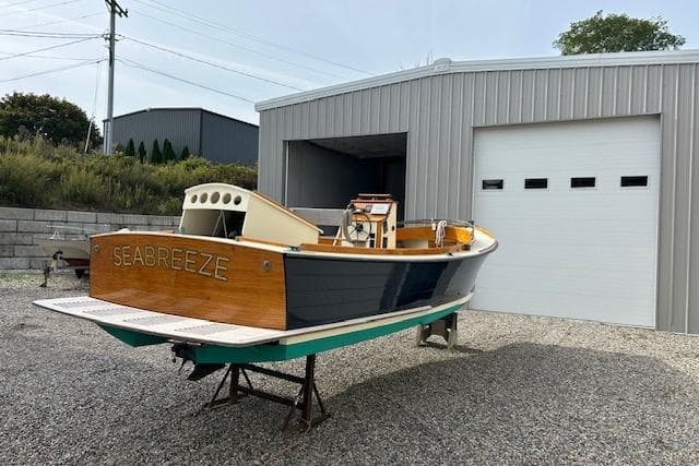 First Light Monomoy 26 boat 'Seabreeze' from 2016, displayed outside a metal garage.