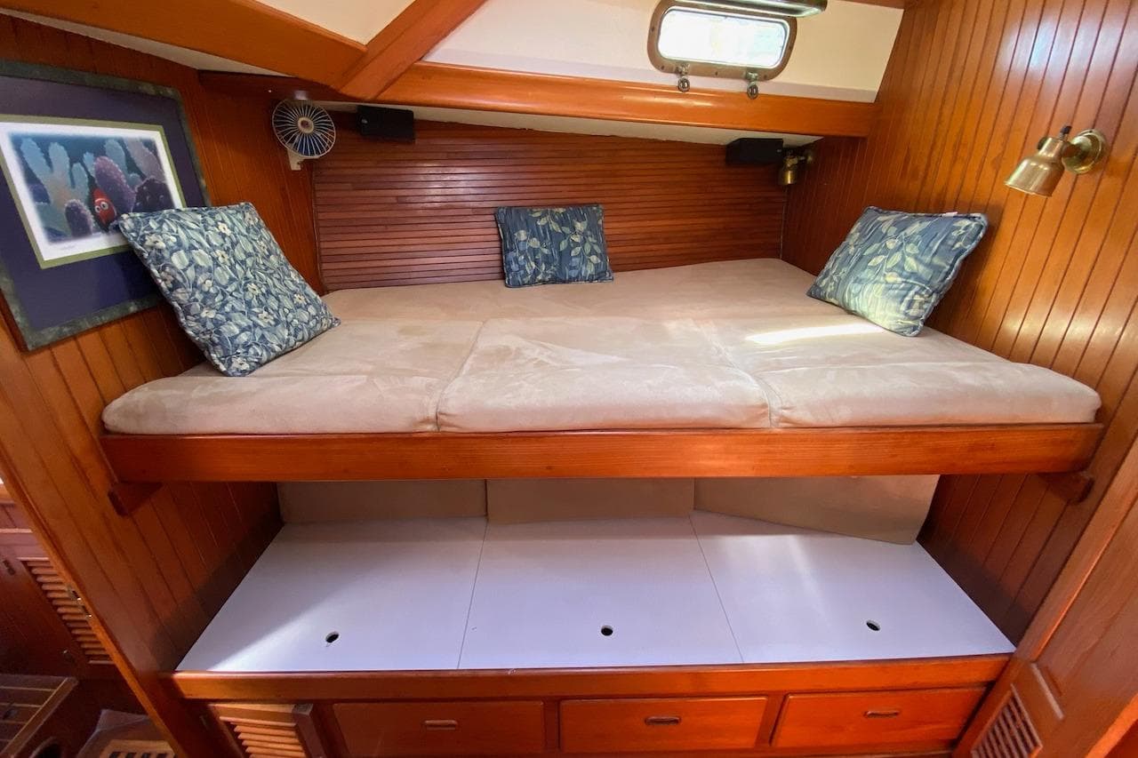 Cozy cabin bed in 1985 Liberty 458 yacht with wooden paneling and decorative pillows.