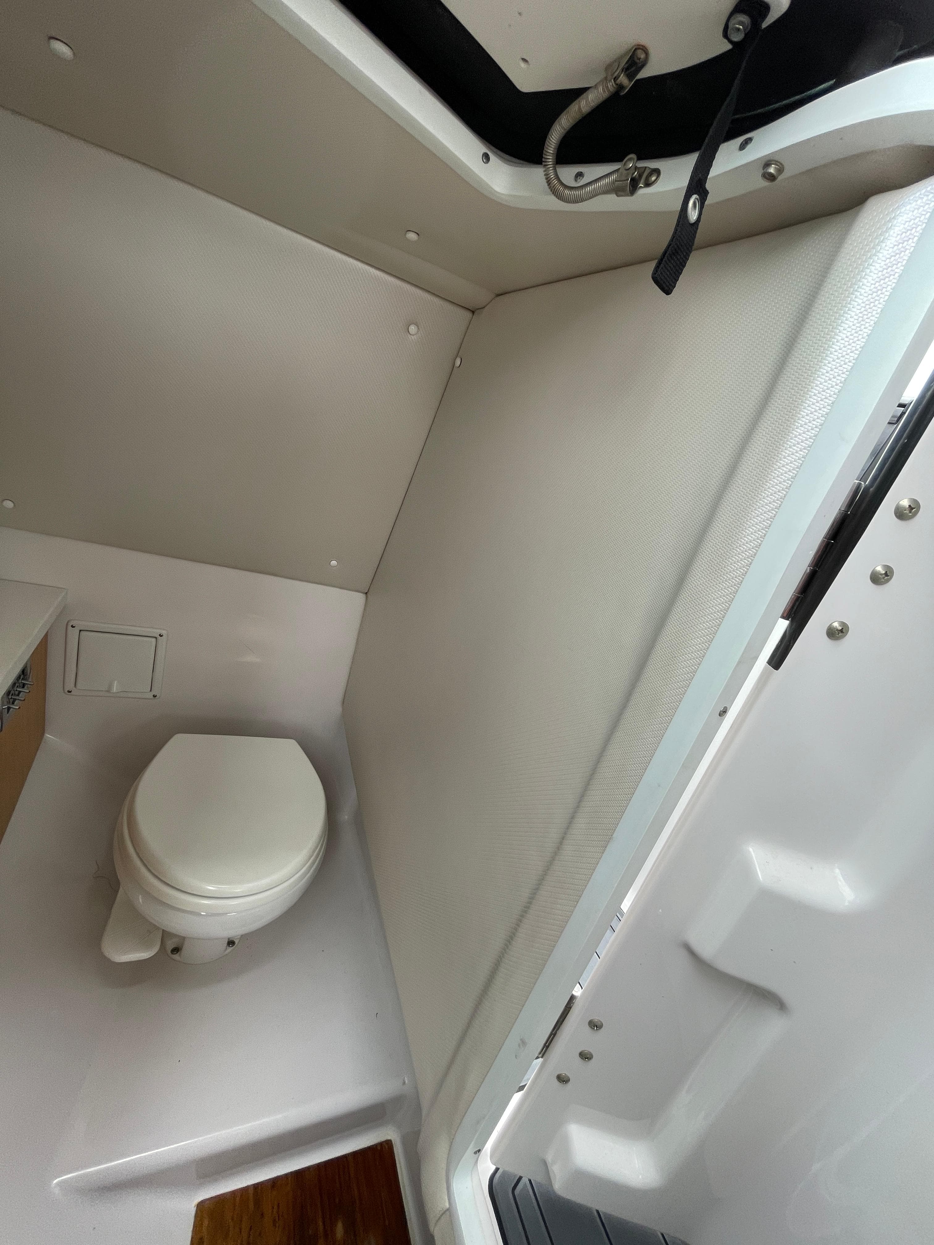2004 Sea Ray 220 Sundeck interior with compact marine toilet and storage space.