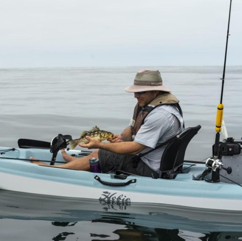 Man fishing on a 2023 Hobie Passport 12.0 kayak, holding a fish.