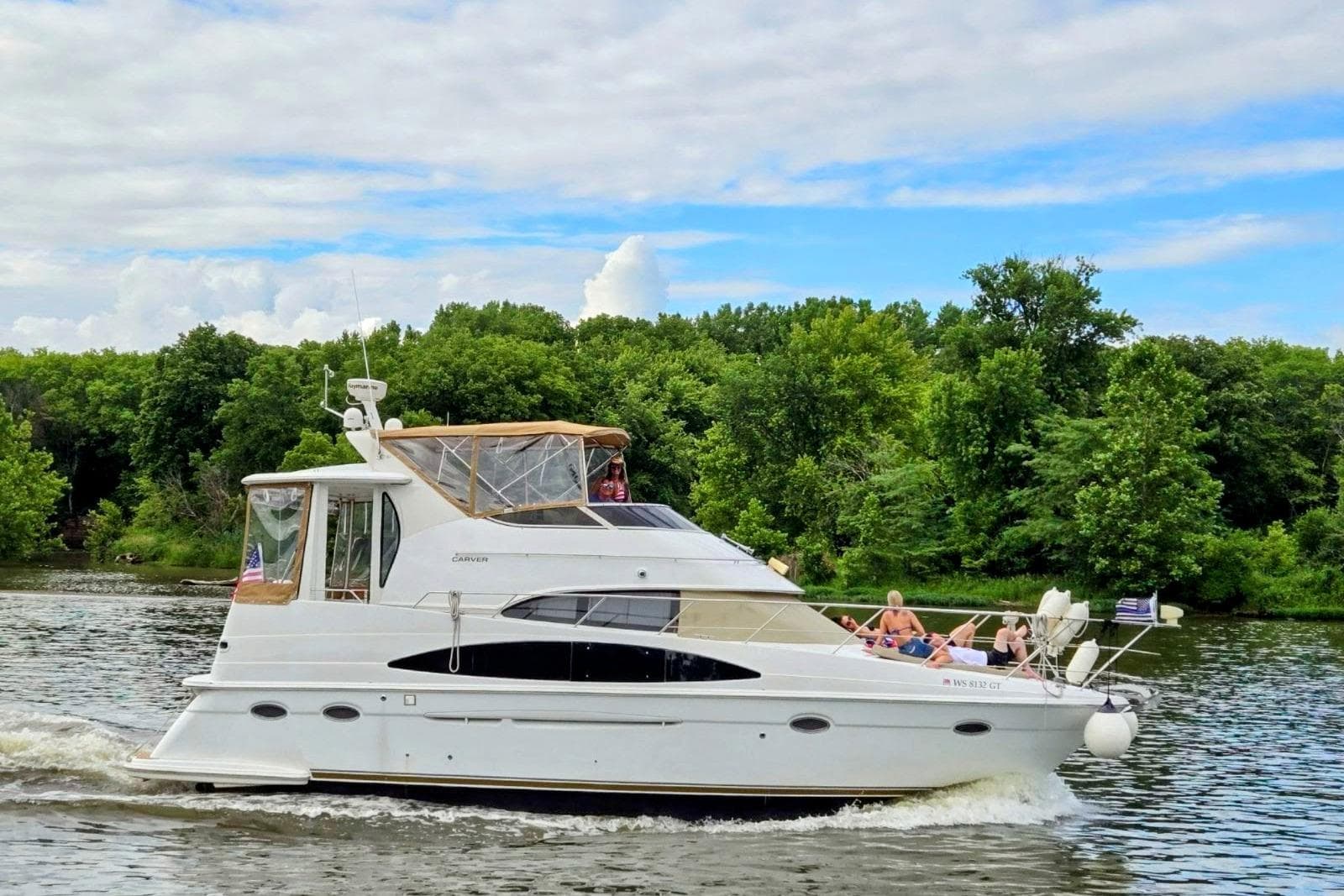 2000 Carver 396 Motor Yacht cruising on a scenic river with lush green trees.
