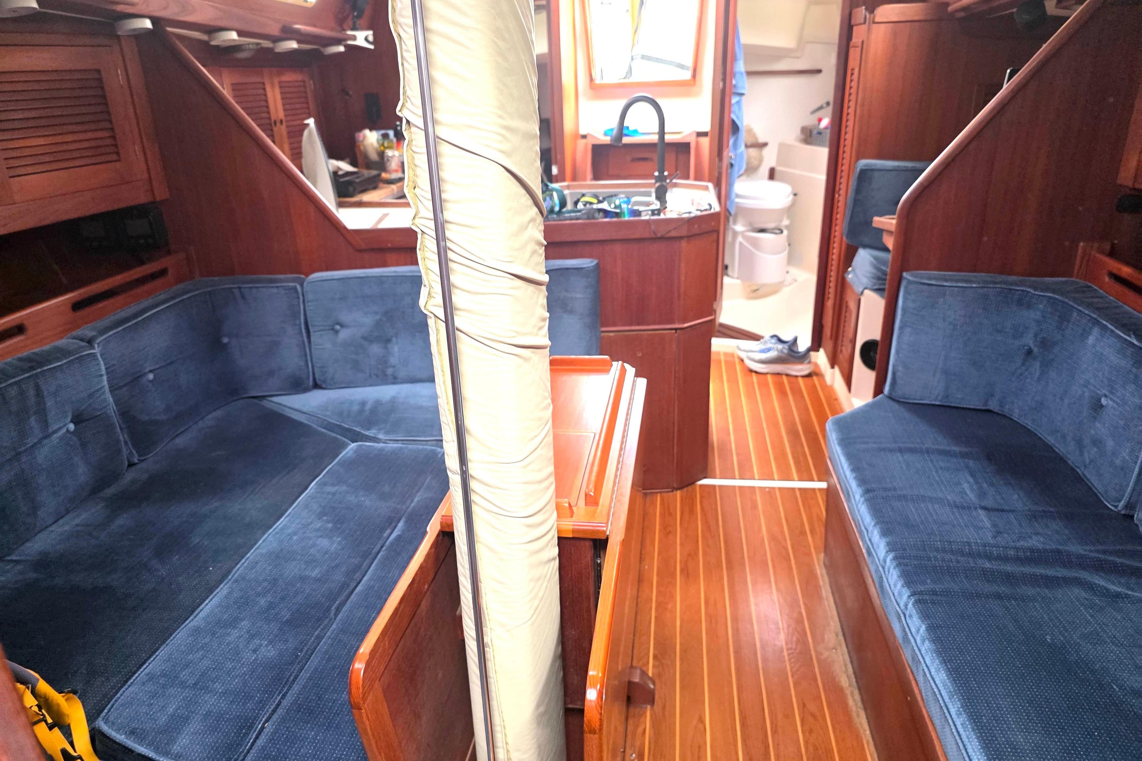 Interior of a 1990 Tartan 372 sailboat with blue seating and wooden finishes.