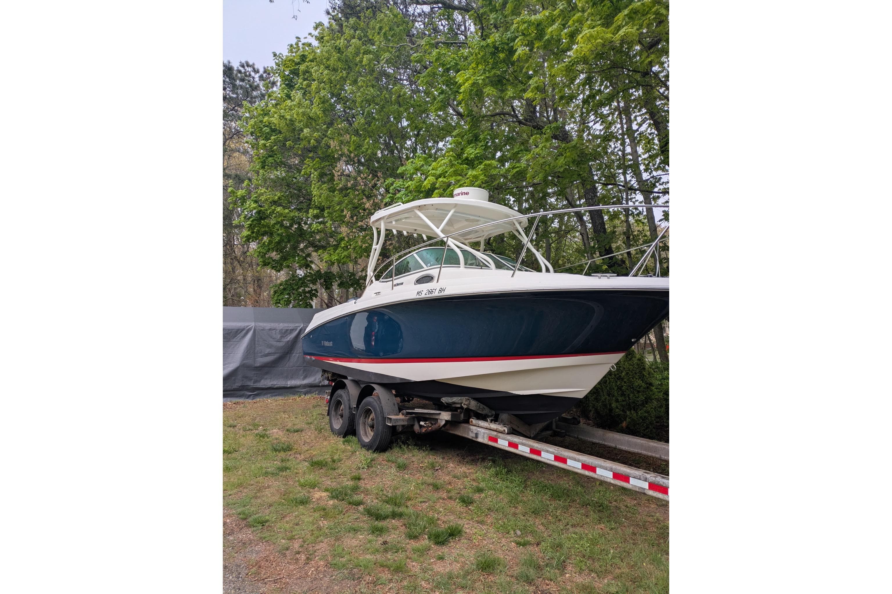 2016 Wellcraft 252 Coastal boat on trailer, surrounded by lush green trees.