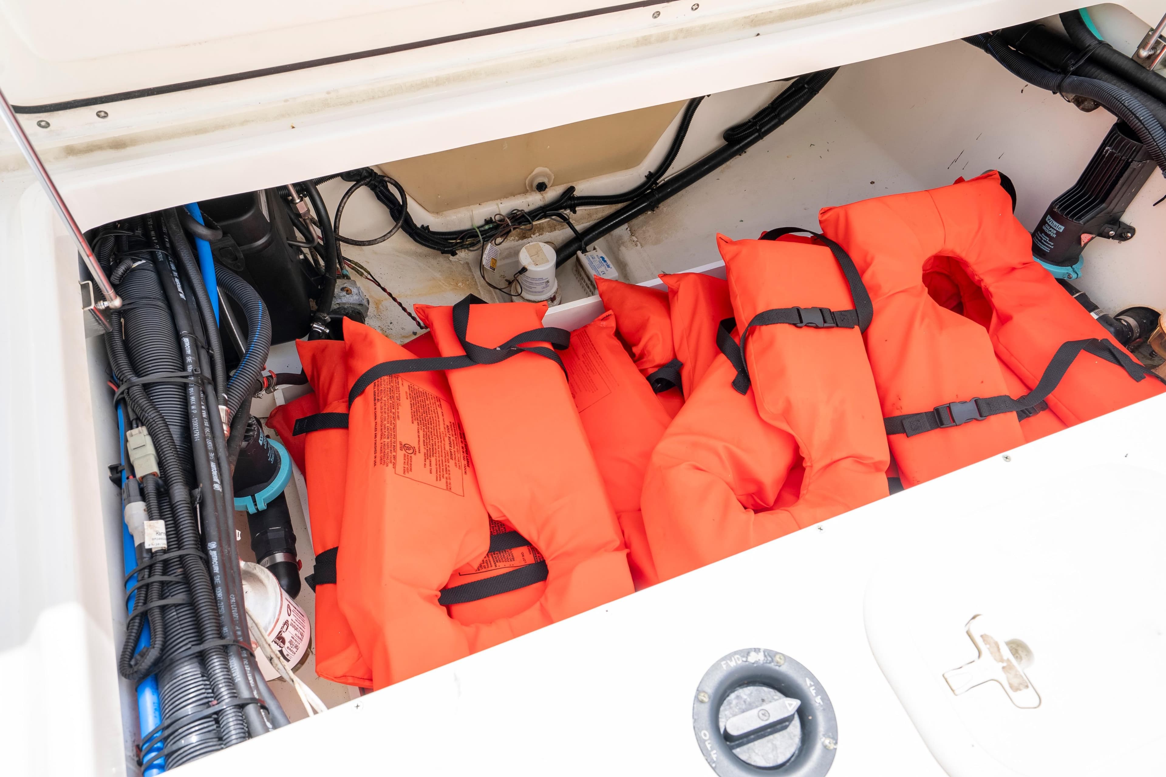 Storage compartment with orange life jackets on a 2013 Boston Whaler 320 Outrage boat.