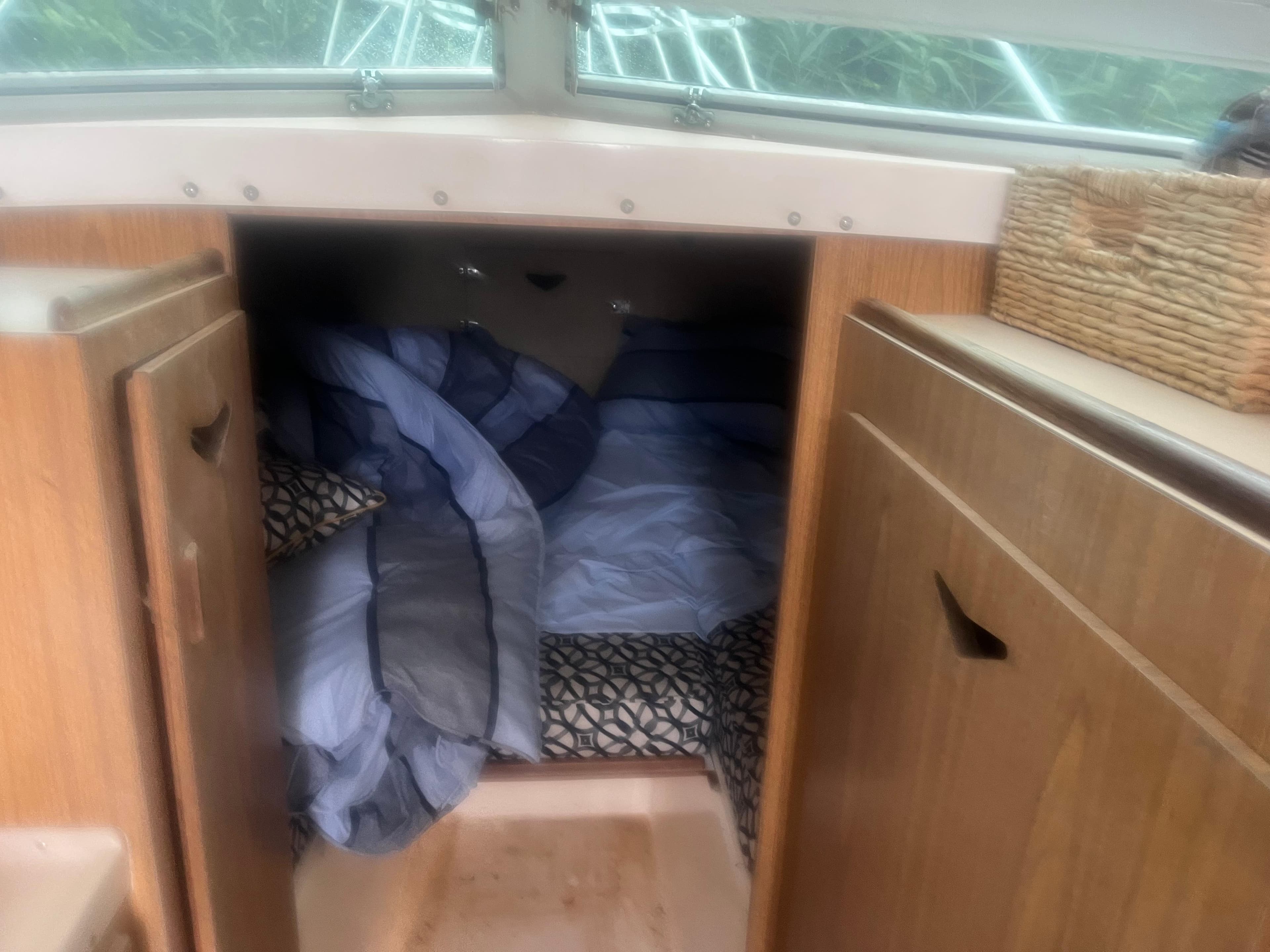 Cozy cabin interior of 1973 Bertram 28 Flybridge Cruiser with bedding and storage.