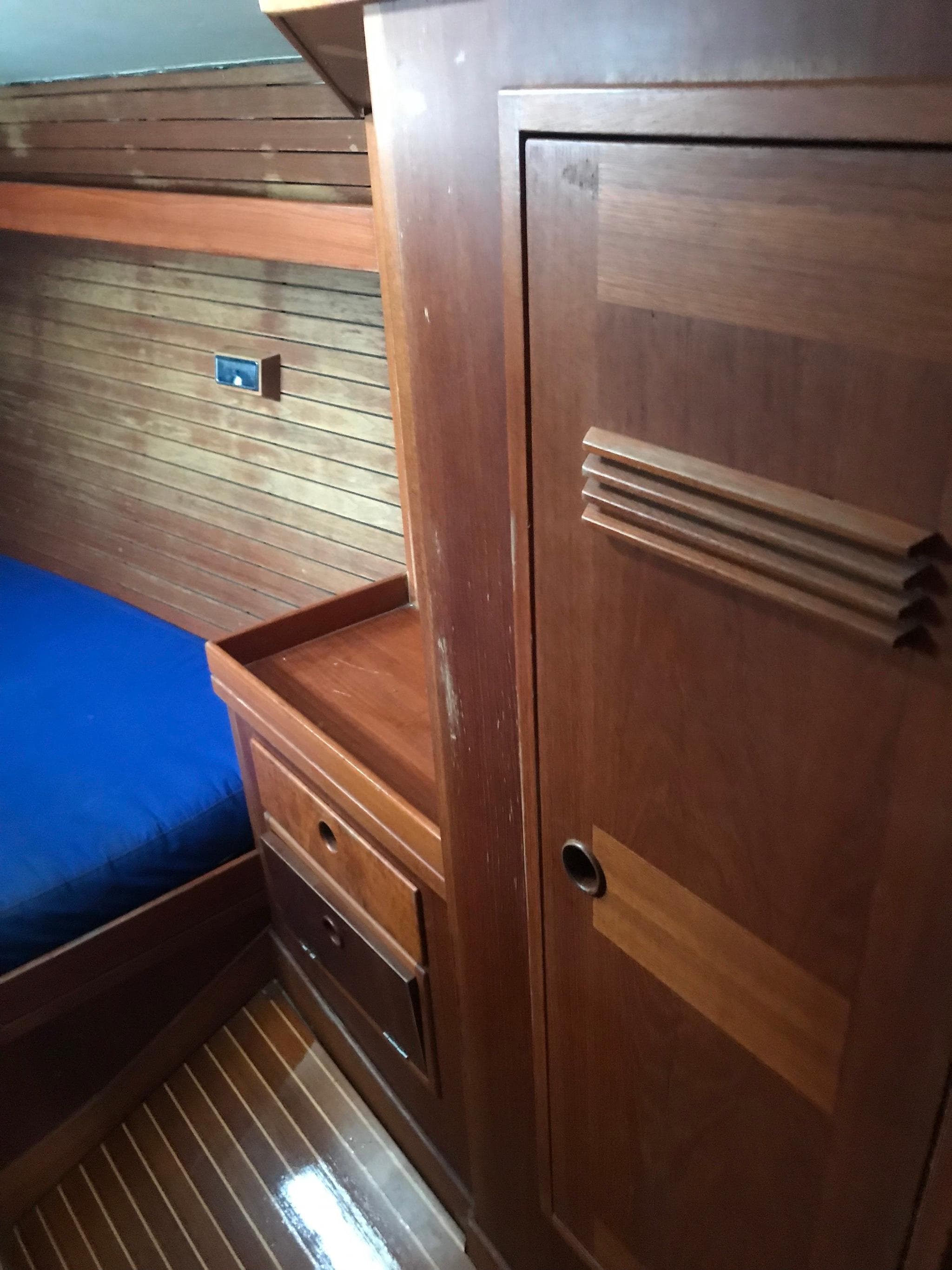 Interior of 1986 Baltic Custom Farr 44 yacht with wooden cabinetry and blue bedding.