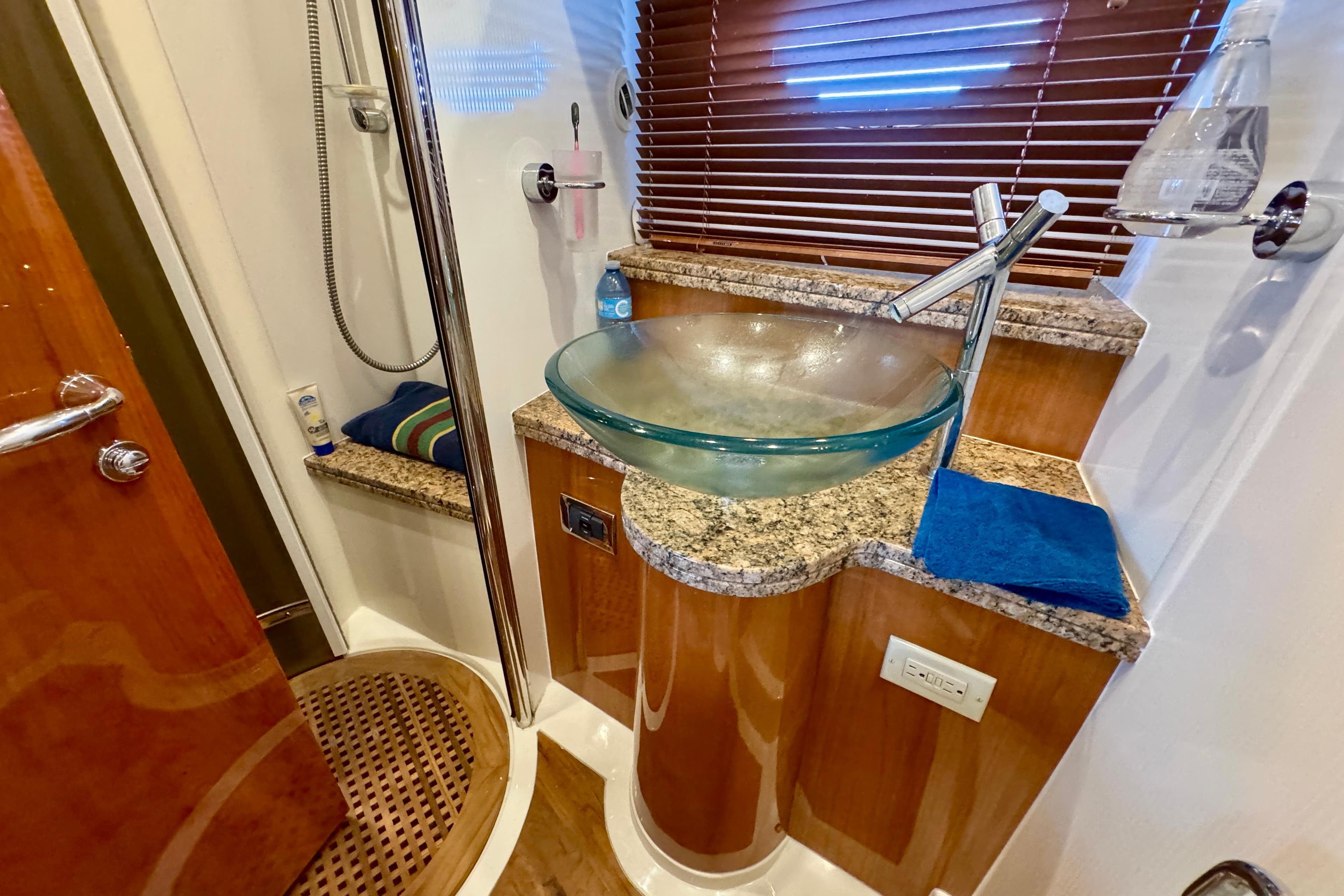 Luxurious bathroom in 2005 Sunseeker Manhattan 50 yacht with glass sink and wooden accents.