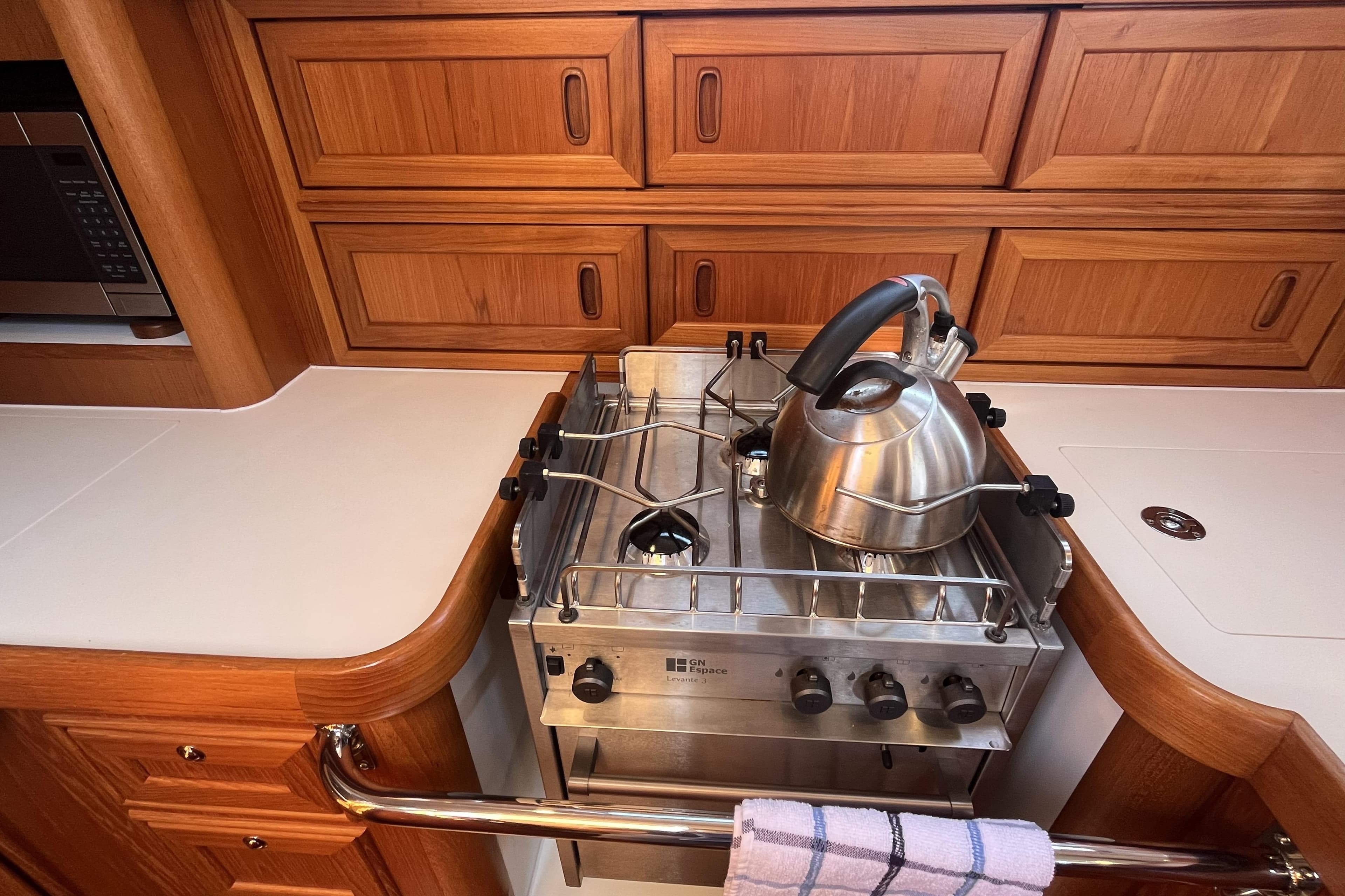 Wooden yacht kitchen with stove, kettle, and cabinetry in a 2017 Rustler 37.