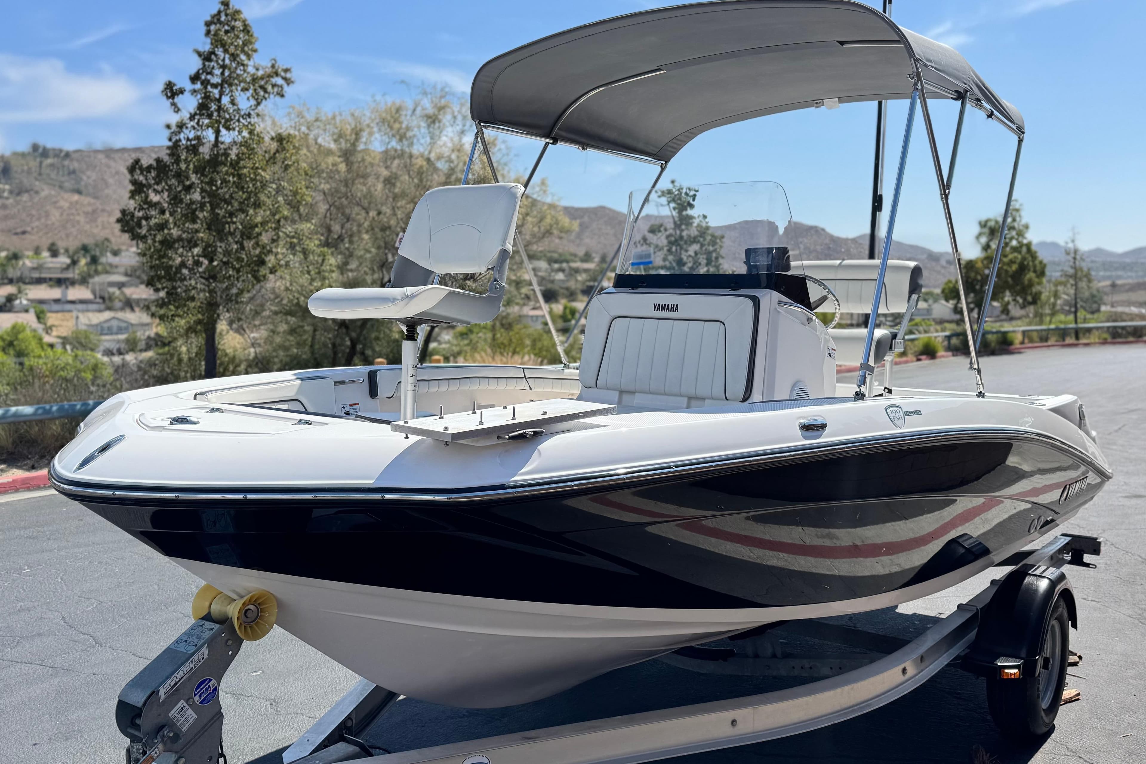 2016 Yamaha Boats 190 FSH Deluxe on trailer, featuring sleek design and canopy.