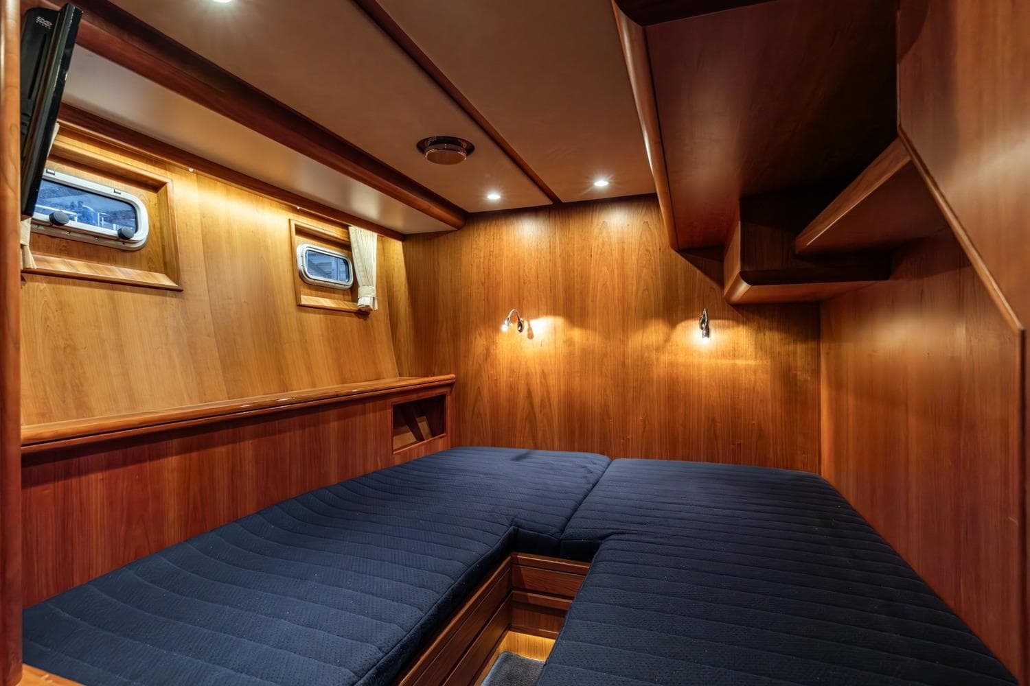 Luxurious wooden cabin interior of 2007 Silverline Trawler 1500 with cozy bedding.
