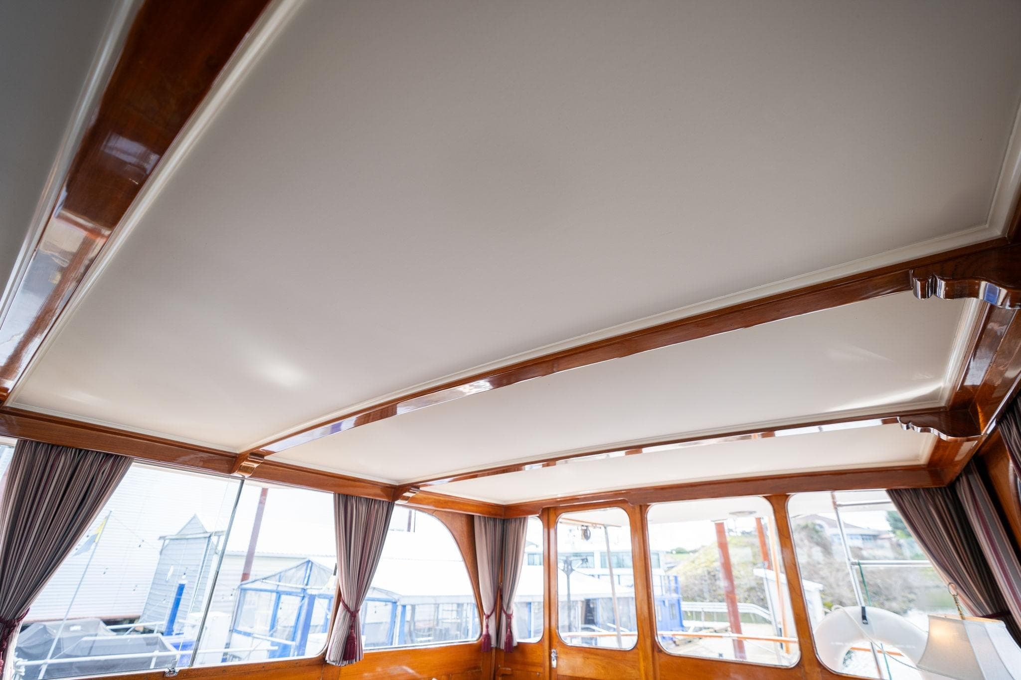 Interior view of 1965 De Vries Lentsch 64 Motoryacht with elegant wood trim and large windows.