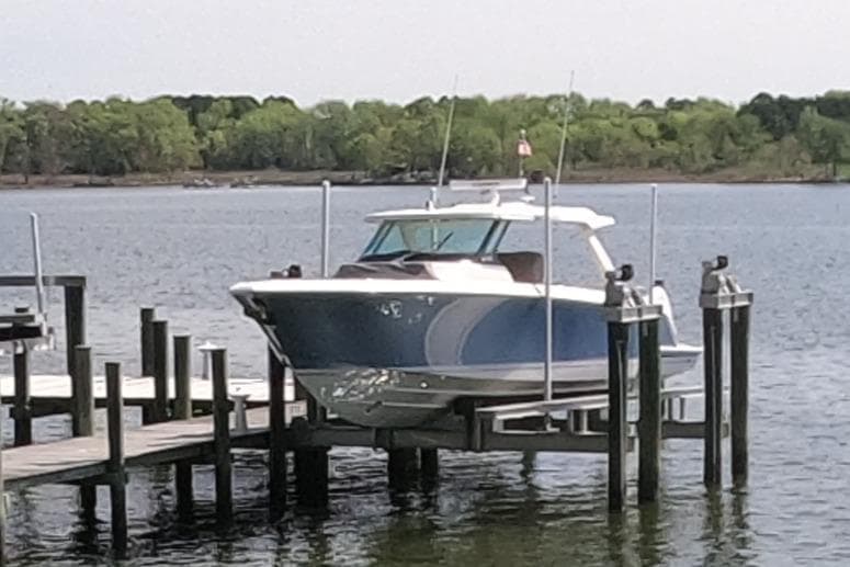 2024 Tiara Yachts 43 LS docked on a serene lake with lush green background.