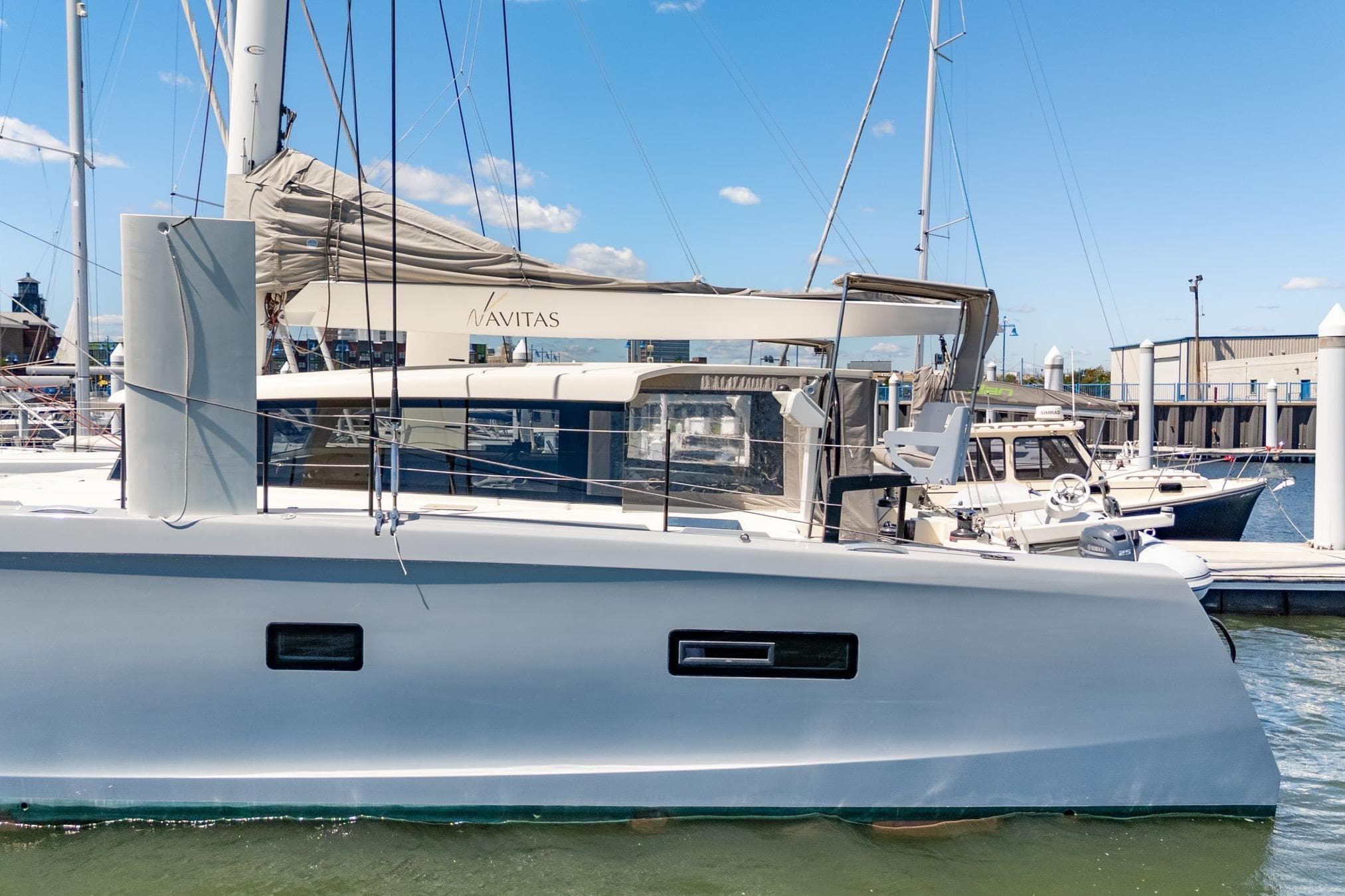 2019 Itacatamarans 14.99 catamaran docked at marina under clear blue sky.