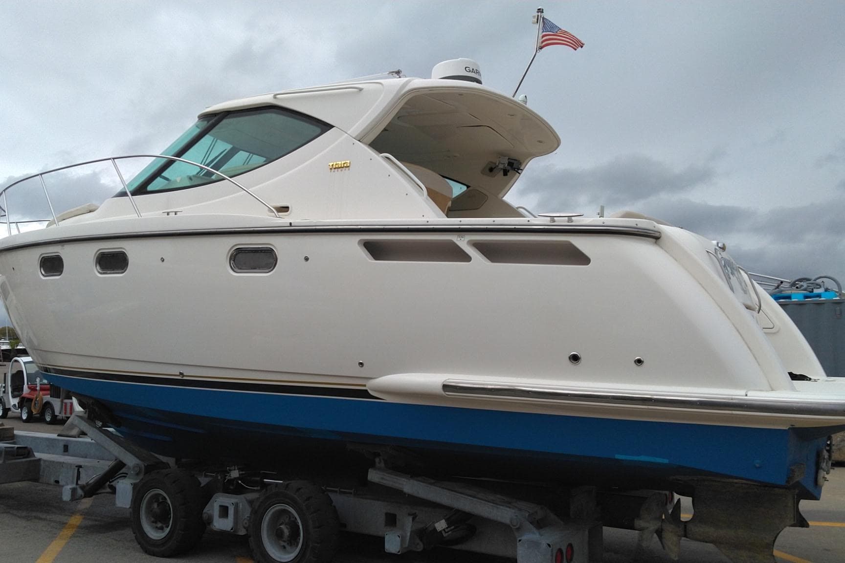 2009 Tiara Yachts 3500 Sovran boat on trailer, American flag, cloudy sky.