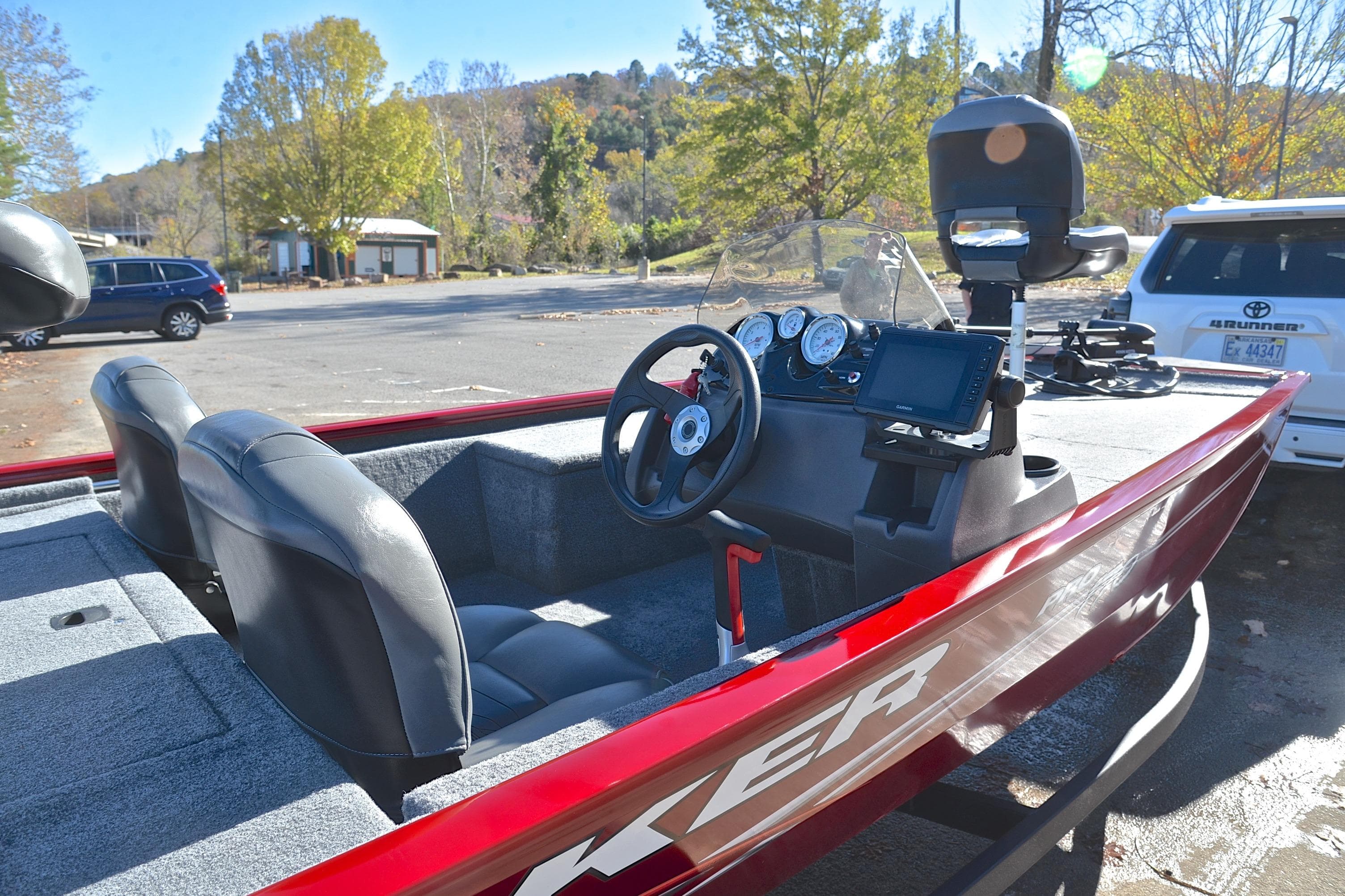 2024 Tracker Pro 170 boat with red exterior and modern dashboard in a scenic parking area.