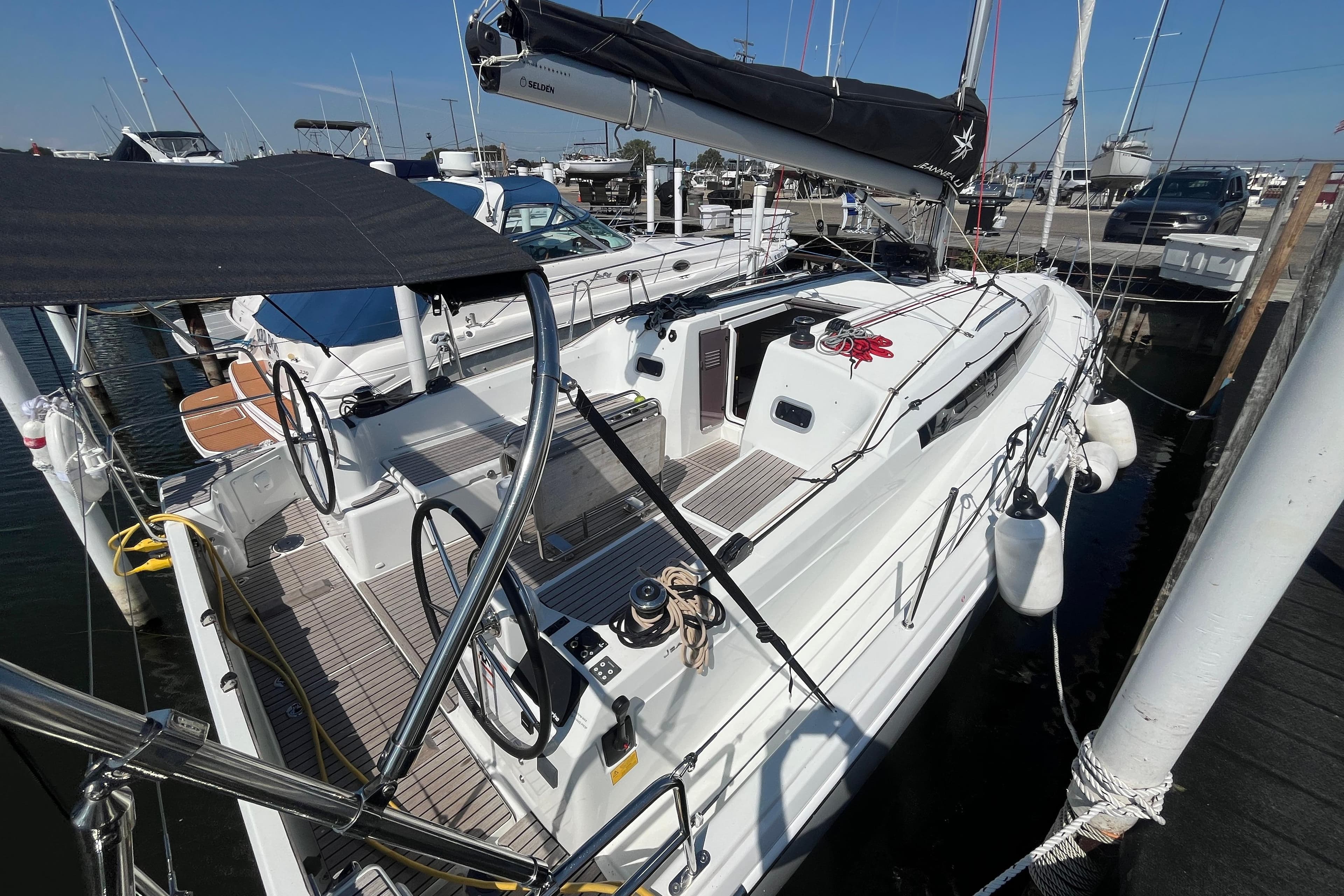 2024 Jeanneau 380 sailboat docked at marina, featuring dual steering wheels and sleek design.